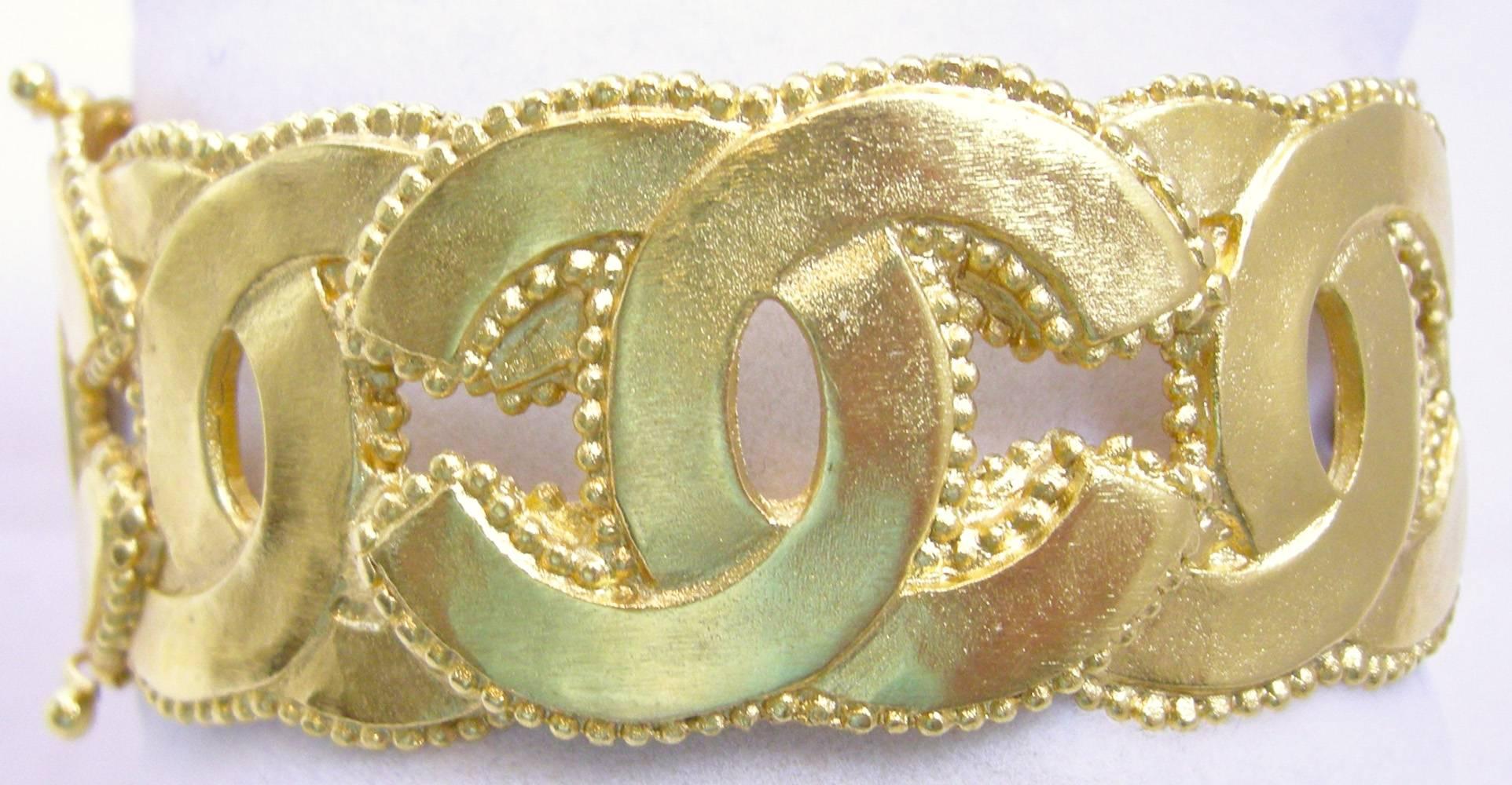 This is a wonderful vintage Chanel cuff bracelet.  It has the famous Chanel “C” going around with beaded trim.  It is set in a gold tone metal base metal and has a safety hook on each side for secure closure.  It measures 7” and a little over 1”