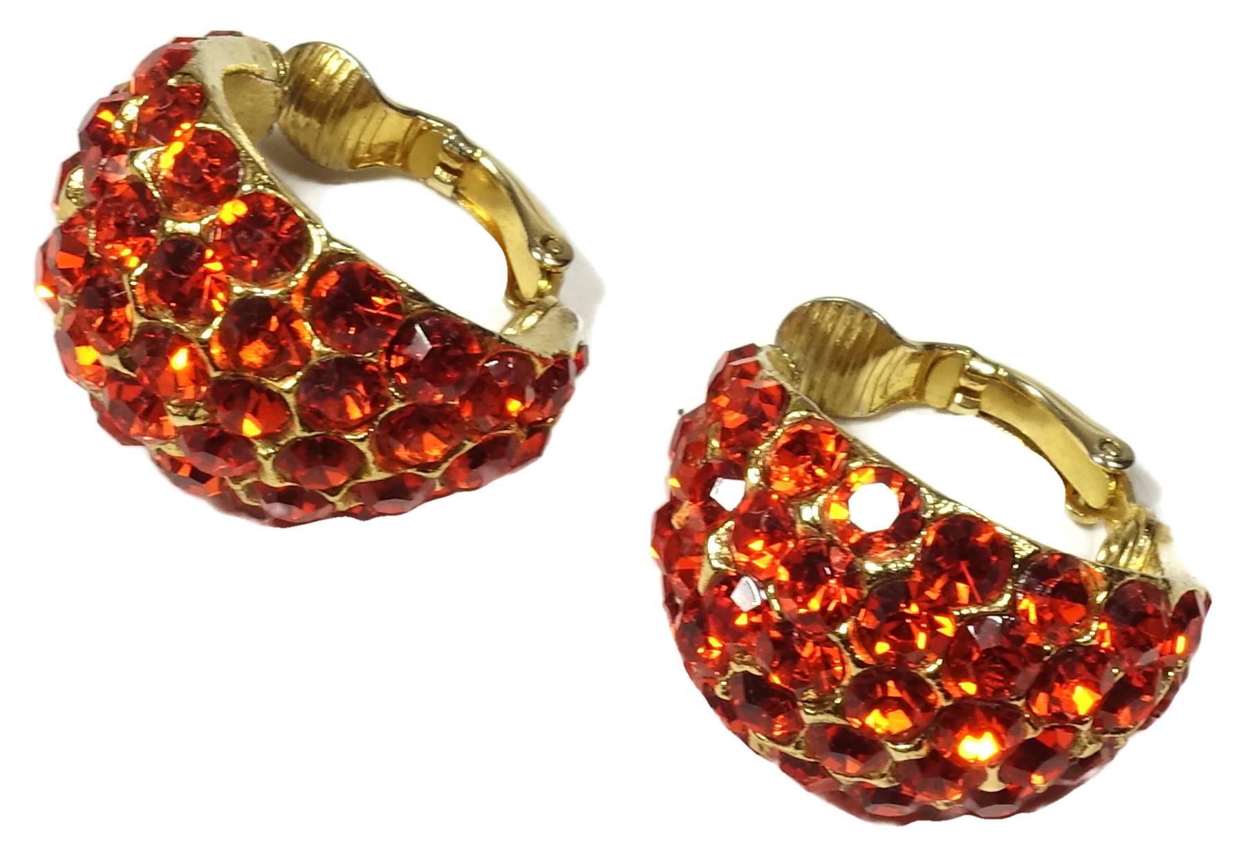 These sparkling clip earrings have a hoop design encrusted with brilliant orange rhinestone.  They are in a gold tone base metal finish and measure 2” around and 7/8” at its widest point.  These earrings are in excellent condition.