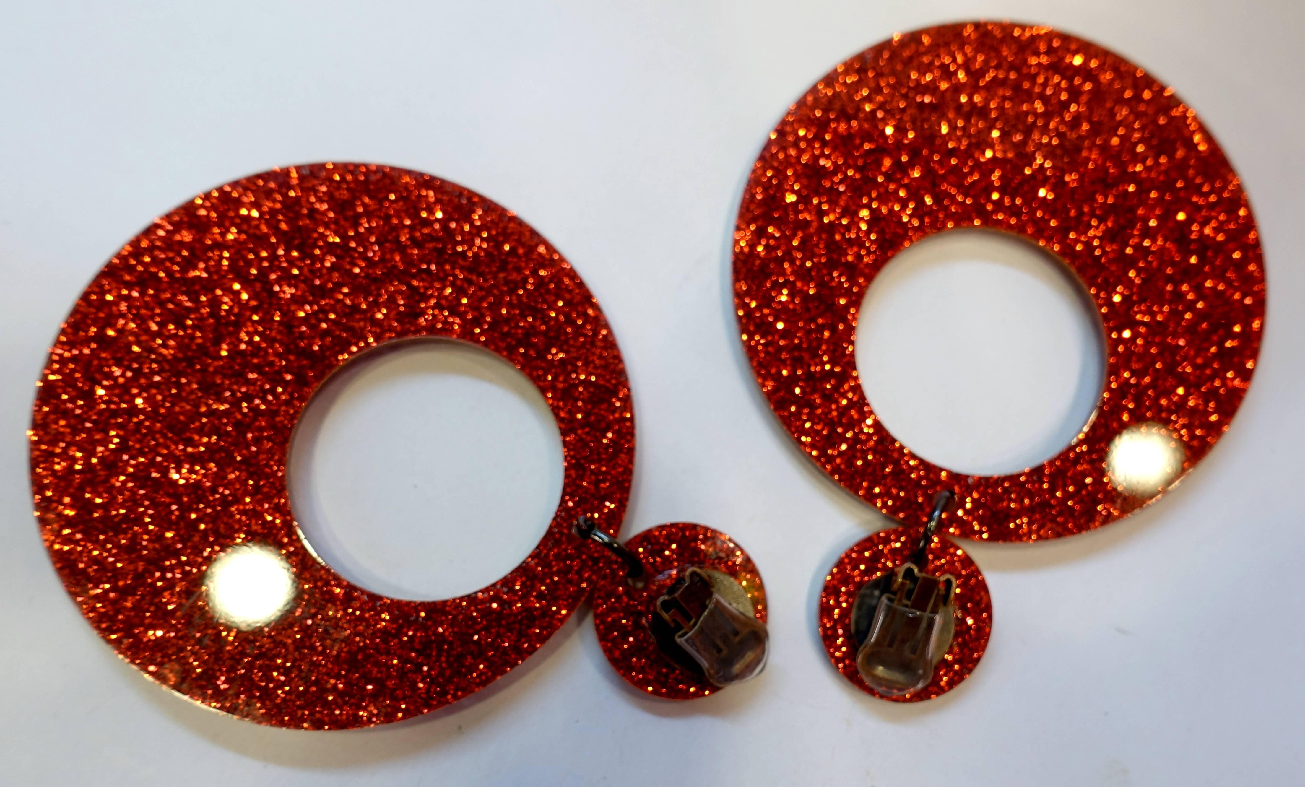 These clip earrings are so campy, I had to buy them.  They each have a red plastic iridescent round disk at the top that connects to a huge dangling red hoop at the bottom. They measure 4-1/8” long and 3-1/4” wide.  You’ll certainly be noticed in
