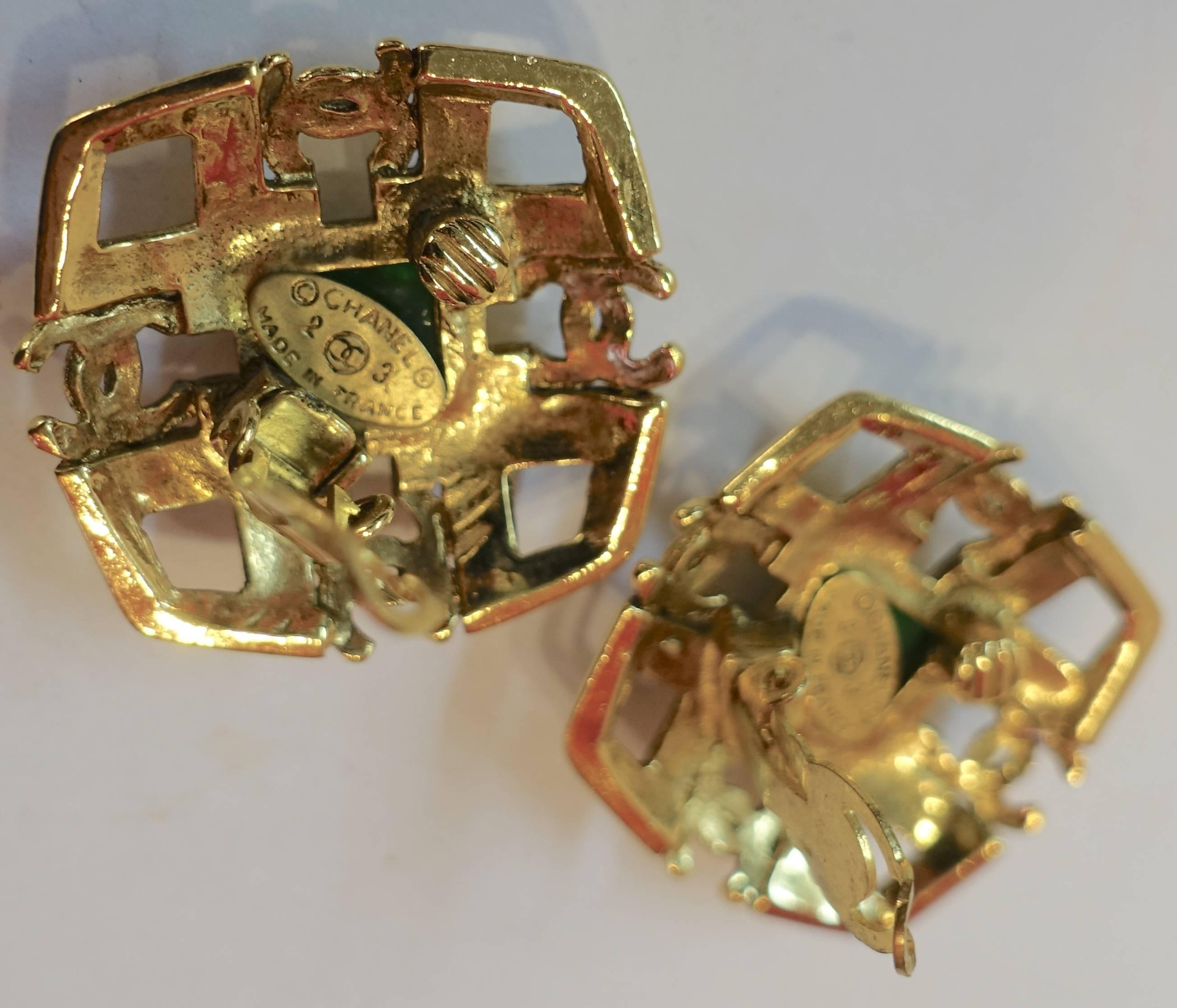 These vintage clip Chanel earrings are from season 23.  They are different and elegant.  It has a square open work design with the double Cs on each side.  The center has the old green Gripoix center.  It has a gold plated tone metal finish and are