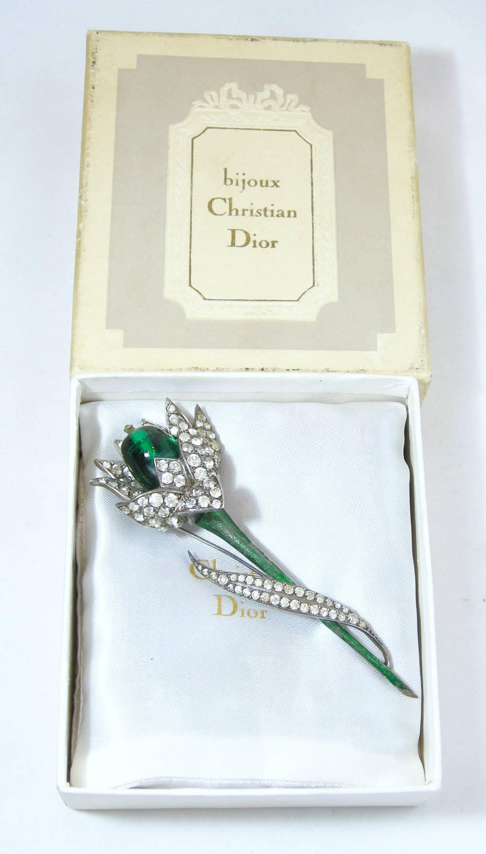 This is a very rare 1960s Dior flower brooch in its original box and dust cover.  It is 4” high and 1-3/4” wide.  The stem is green enamel and the branch and flower petals are crystals with a Green Gripoix center in the flower.  This brooch has been