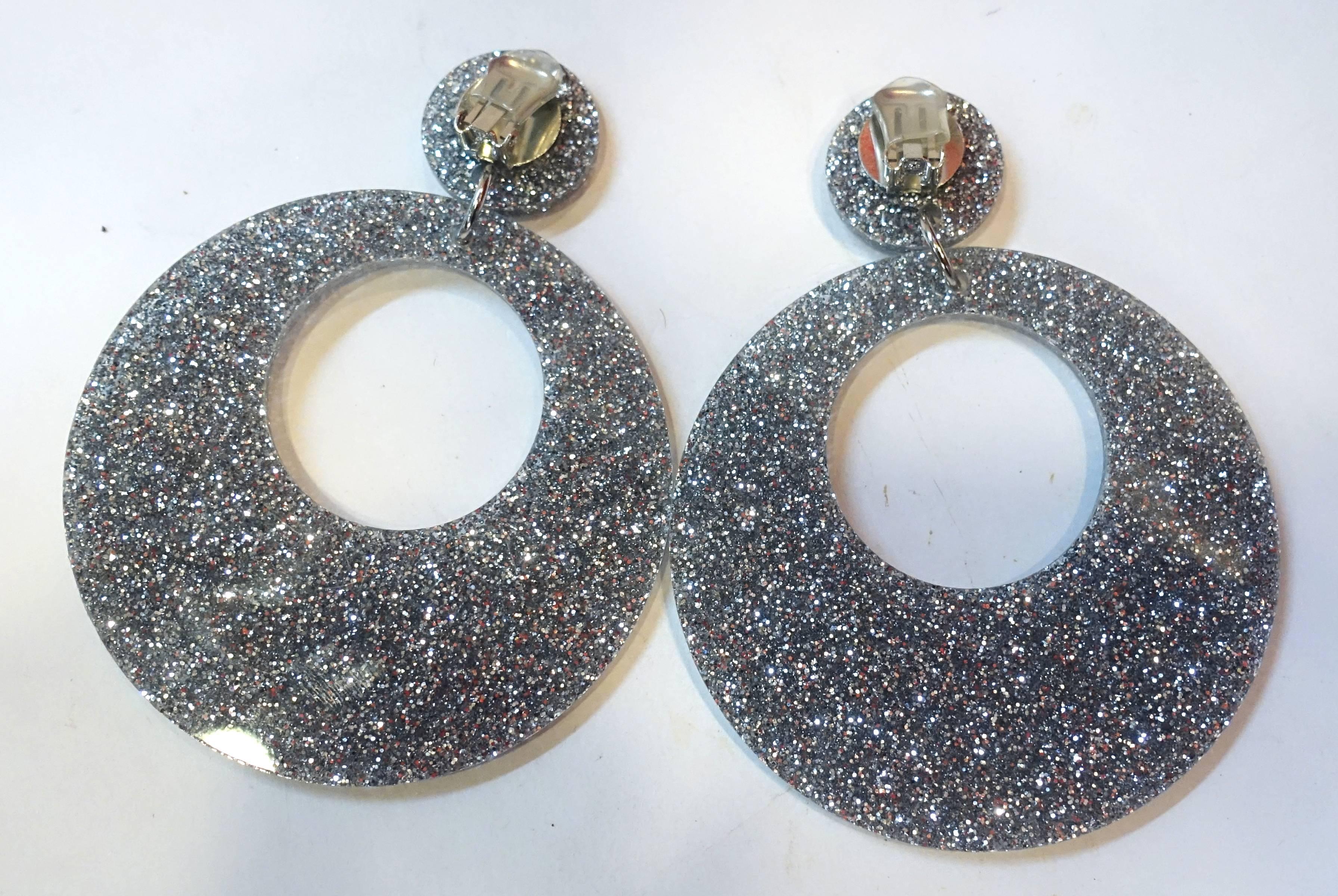 These clip earrings are so campy, I had to buy them in grey. They each have a grey plastic iridescent round disk at the top that connects to a huge dangling grey hoop at the bottom. They measure 4-1/8” long and 3-1/4” wide. You’ll certainly be