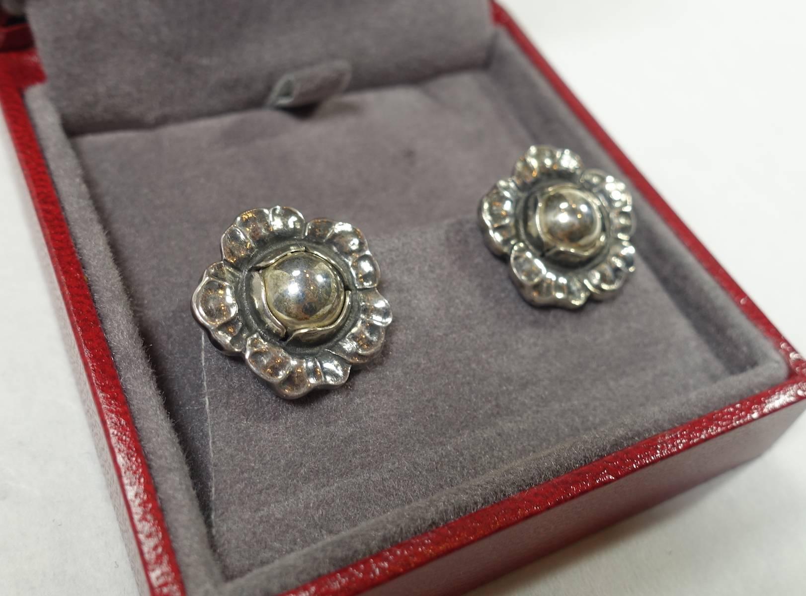 These vintage signed Georg Jensen earrings feature a floral design in a sterling silver setting.  In excellent condition, these clip earrings have a 3/4” diameter, are signed “Georg Jensen 2002 925 Denmark”.