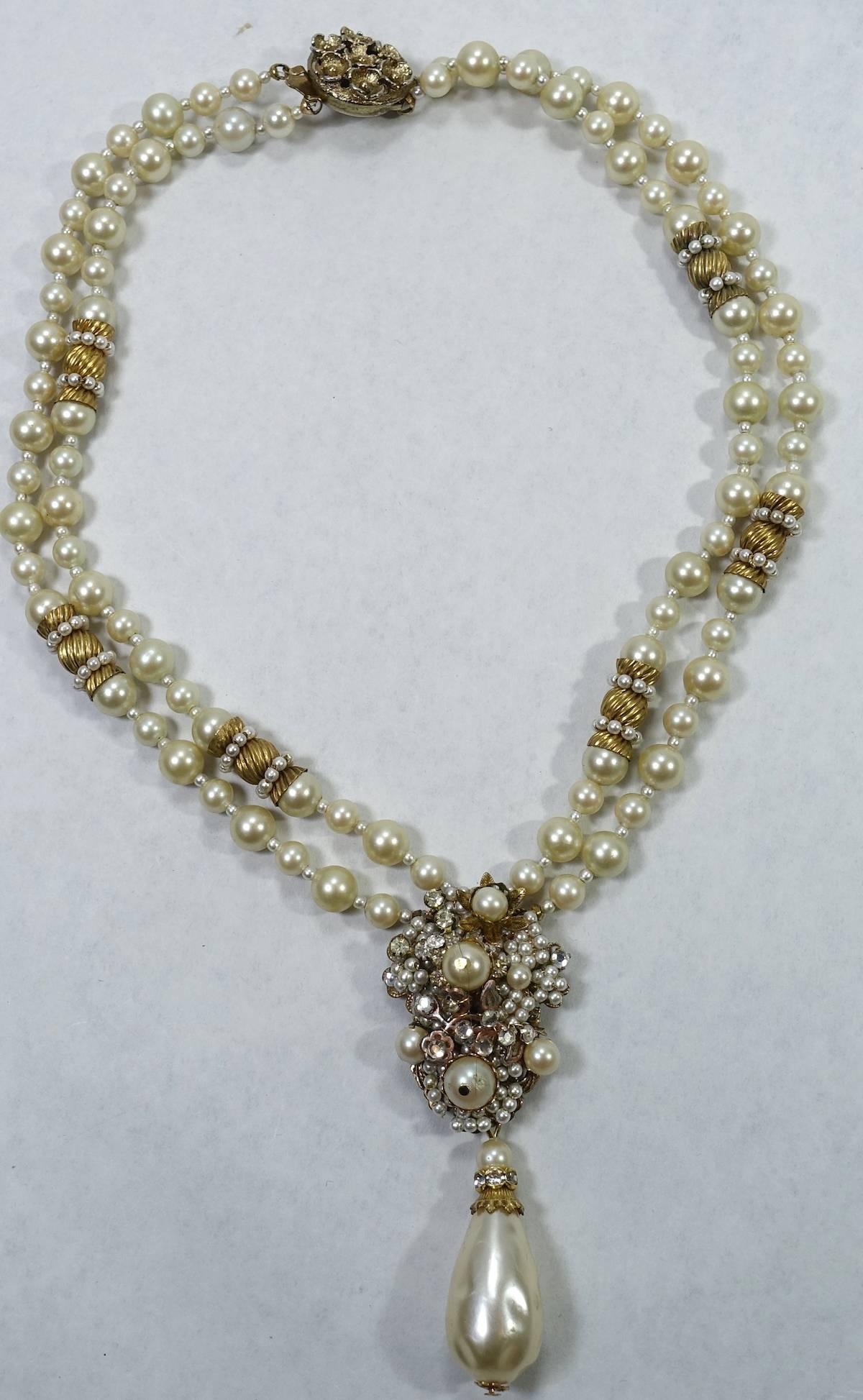 This vintage signed DeMario necklace features faux pearls with rose montee stones in a gold-tone setting.  This necklace measures 17” long x 1/4” wide with a slide in clasp.  The drop is 3-1/4” x 1-1/8” and is signed “DeMario”.  This necklace is in