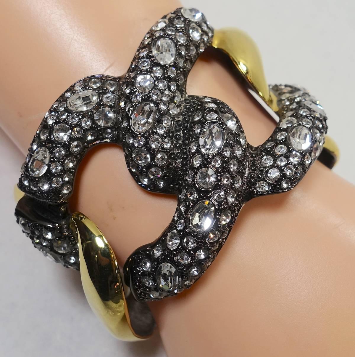 This is a wonderful cuff from Kenneth Jay Lane.  The front has parve rhinestones interlocking in the front while combining a gold tone look on the sides in a Japanned setting.   It measures 2” high at its highest point and is 6-1/2” wide with a side