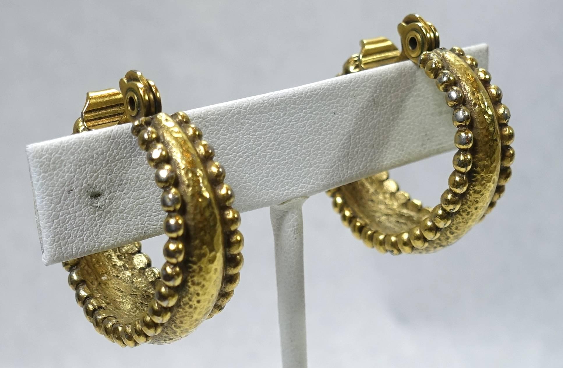 These vintage Yves St. Laurent earrings have a hoop design with gold beaded rims in a gold tone setting.  These clip earrings measure 1-1/8” x 3/8” and signed “YSL”. They are in excellent condition.