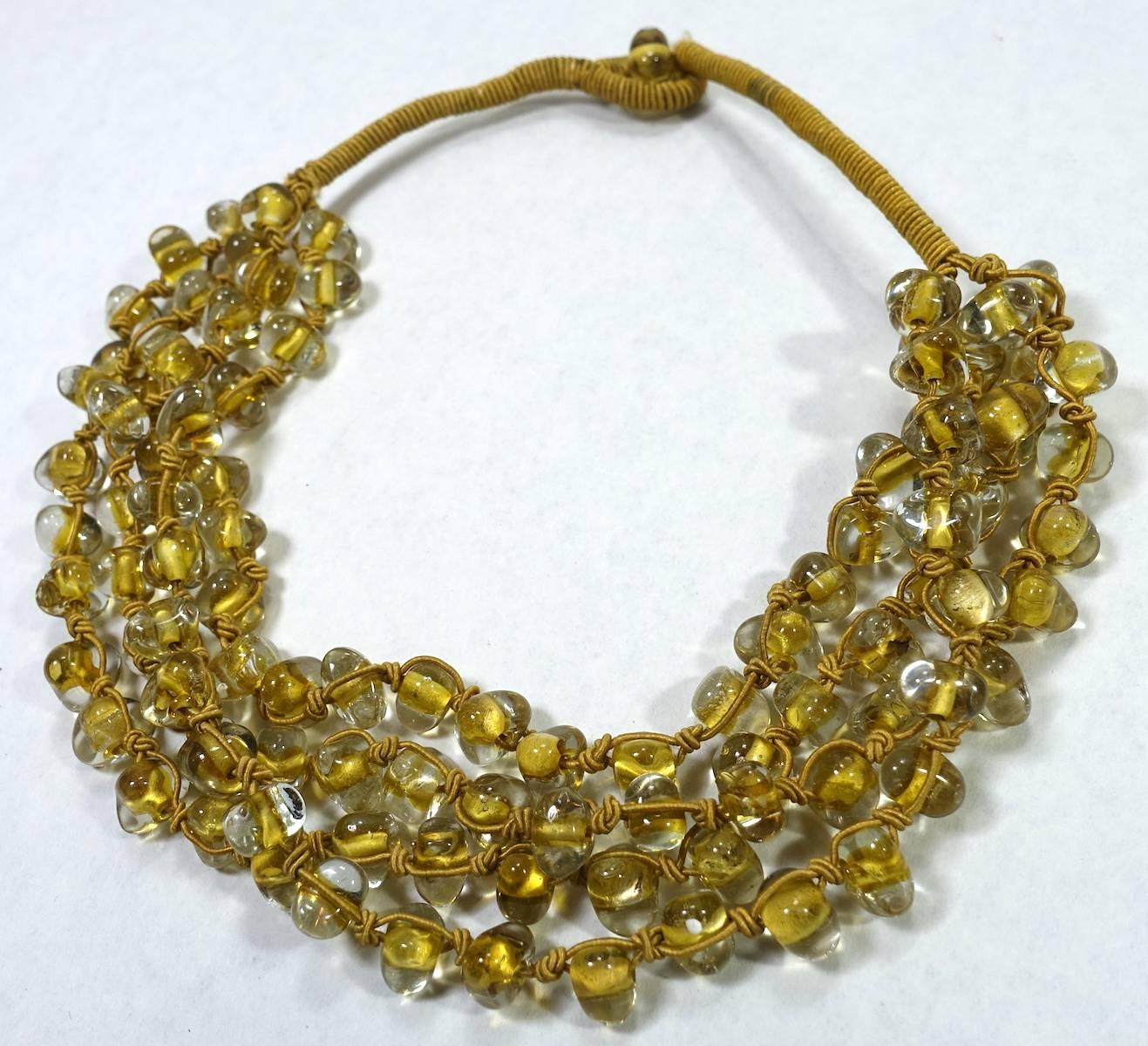 This vintage Art Deco 4-strand necklace features Czech glass beads sewn together with silk threading.  This necklace measures 19” long and each bead is 1/2” x 3/8” with a woven silk toggle closure. The necklace is in excellent condition.