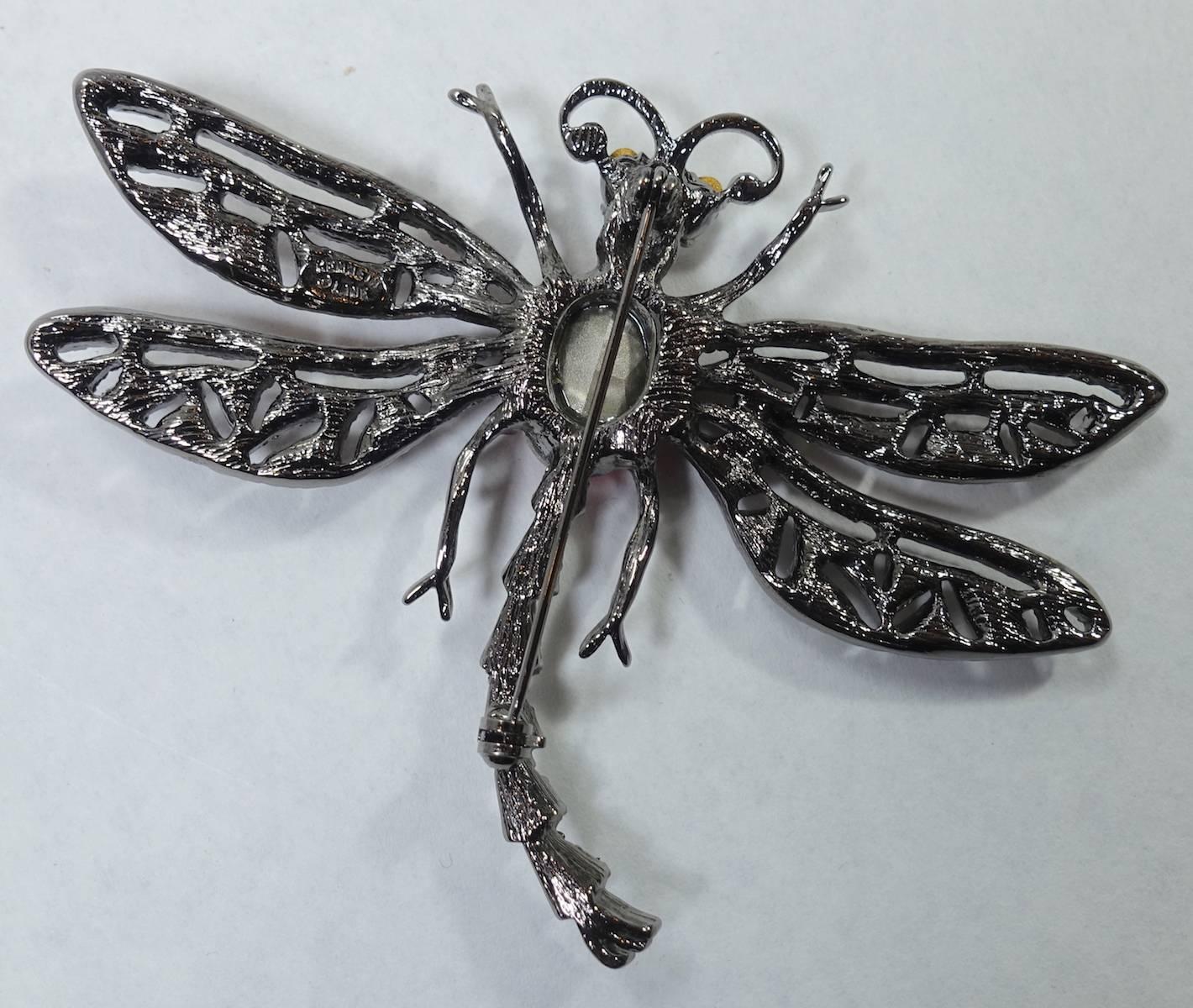 This signed Kenneth Lane brooch features a dragonfly with pink and clear rhinestones in a Japanned setting.  This brooch measures 3-5/8” x 2-3/4” and is signed “Kenneth Lane”. It is in excellent condition.