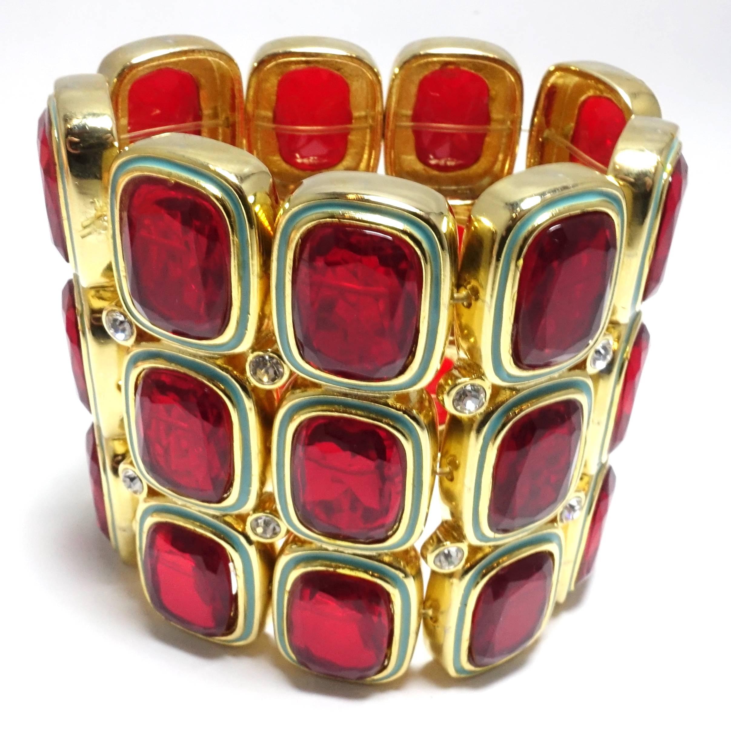 This wide Kenneth Jay Lane stretch bracelet is designed with faux rubies and clear rhinestones with turquoise enameling on the borders.  It is made with a gold tone metal setting.  This bracelet measures 6-1/2” around the inside x 2-7/8” and is