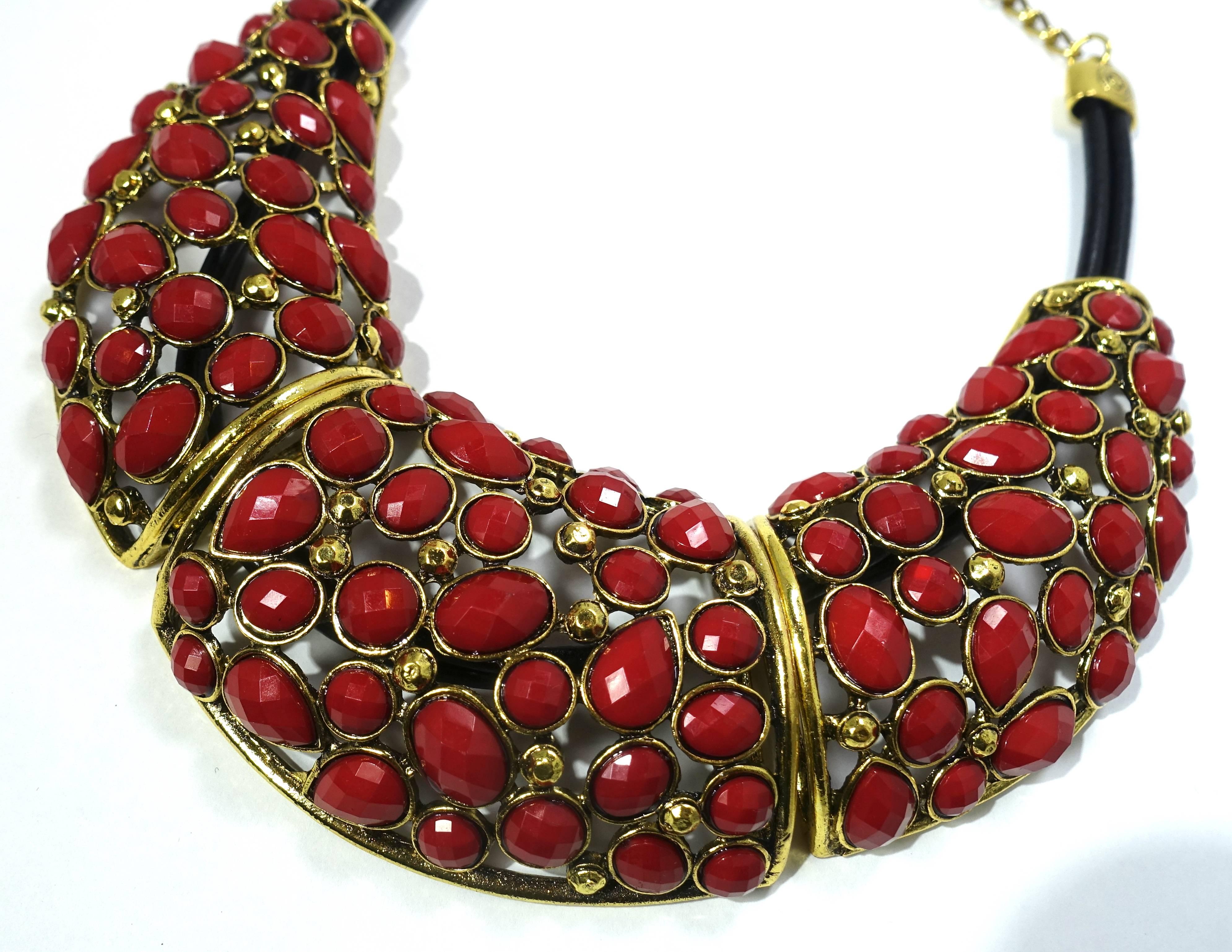 Although this necklace is unsigned, I had the exact same one in blue with his signature.  This Oscar de la Renta necklace has 3 segments with large red stones in a gold tone setting.  They are connected with a double leather rope, which connects to