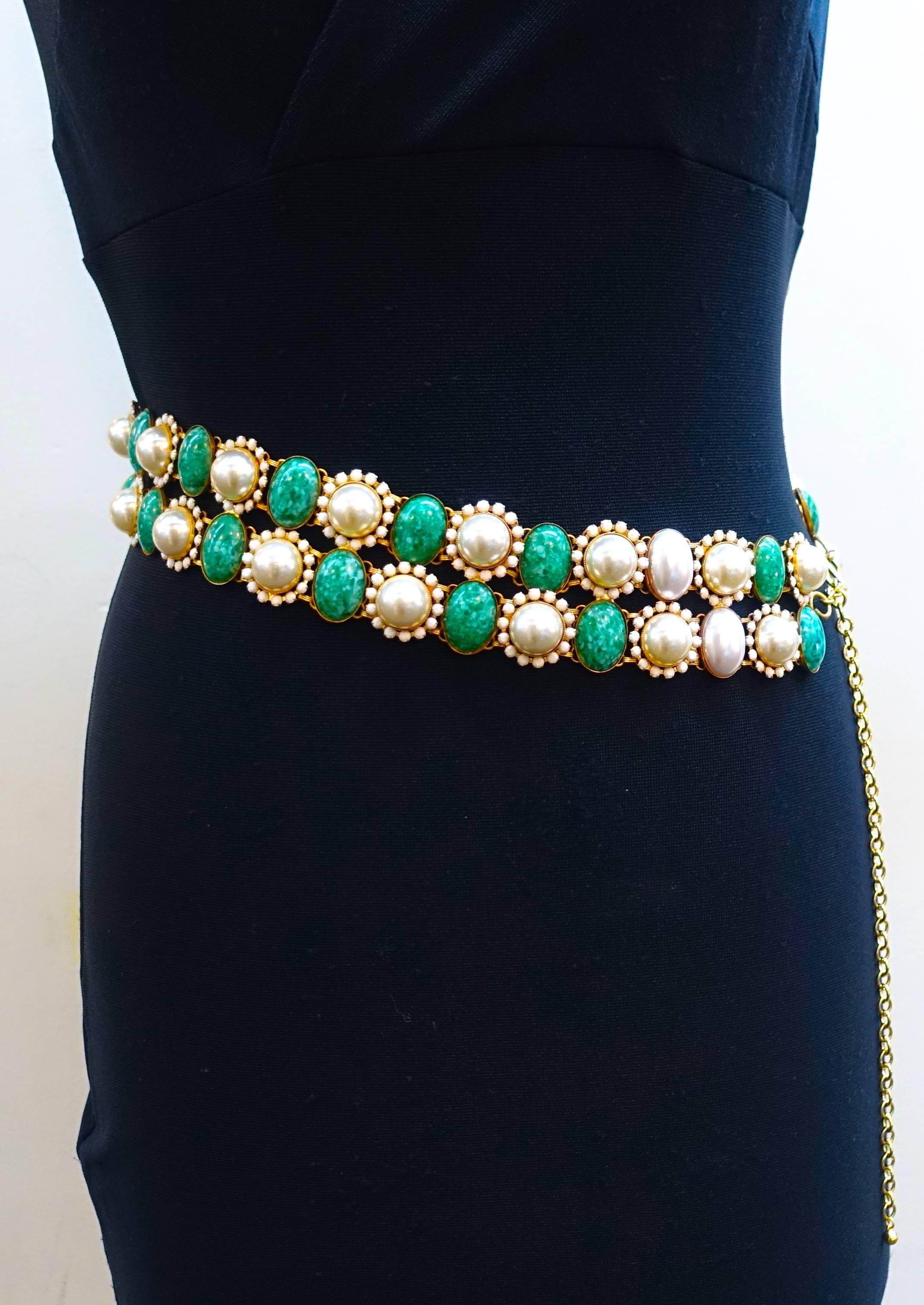 This is an extremely rare 1960’s Kenneth Jay Lane belt.  It has faux white pearls surrounded with small white glass stones giving it a floral look. Alternating with the faux pearls are oval green marbleized stones … all set in a gold tone metal