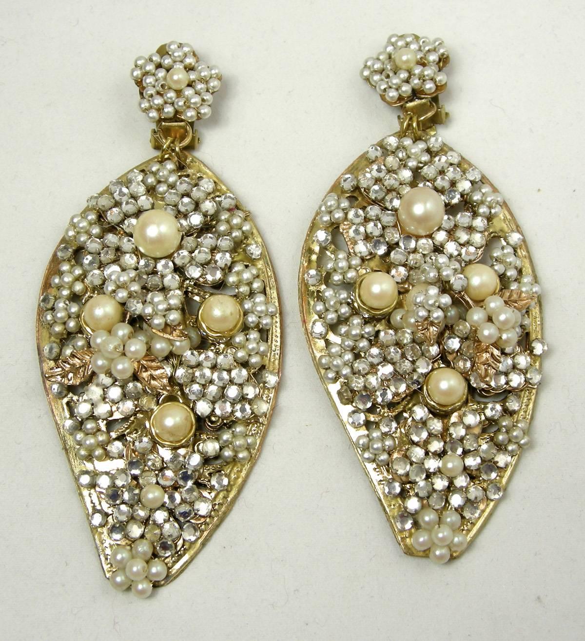 These signed DeMario clip earrings look like Haskell.   It has a faux pearl floral top that connects to a long tear shaped chandelier drop.  The drop has tiny faux pearls accentuated with rhinestones, larger pearls and gold tone leaves.  The