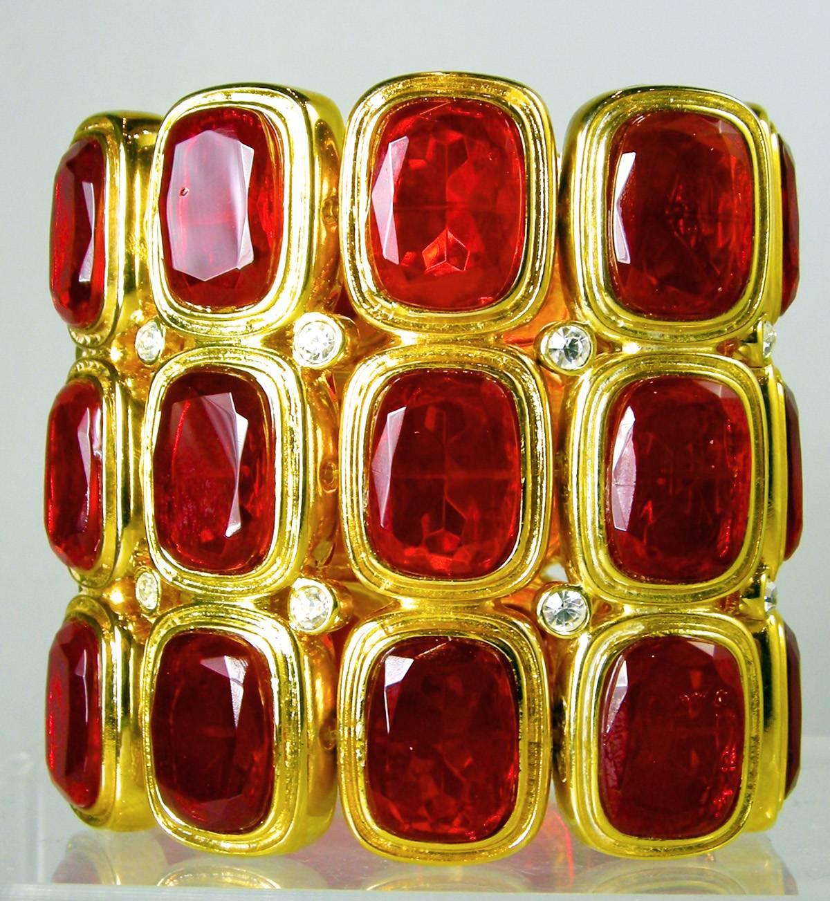 This bracelet has been in great demand and we are lucky to find another one. This Kenneth Jay Lane bracelet features large red rhinestones that are bezel into a gold tone setting. Clear rhinestones accentuate the bracelet throughout. This stretch
