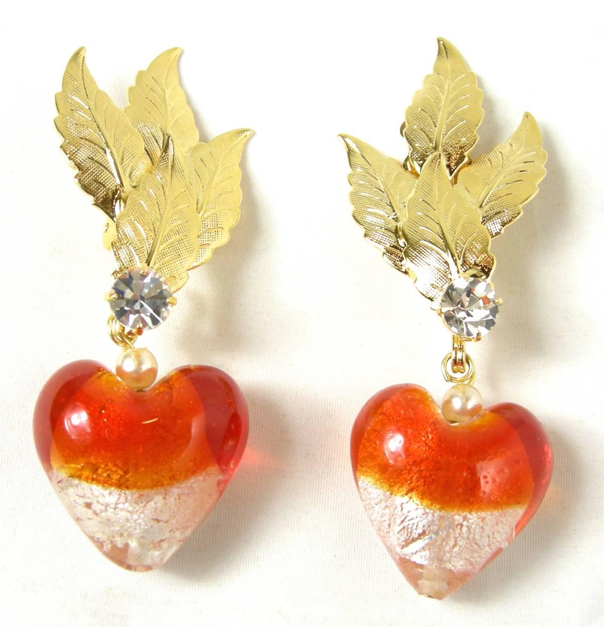 These wonderful heart shaped clip earrings by Robert Sorrell are perfect for Valentine’s Day or any day.  There are three gold leaves on top suspending downward to orange and clear hand blown glass hearts. Each heart is slightly different since each