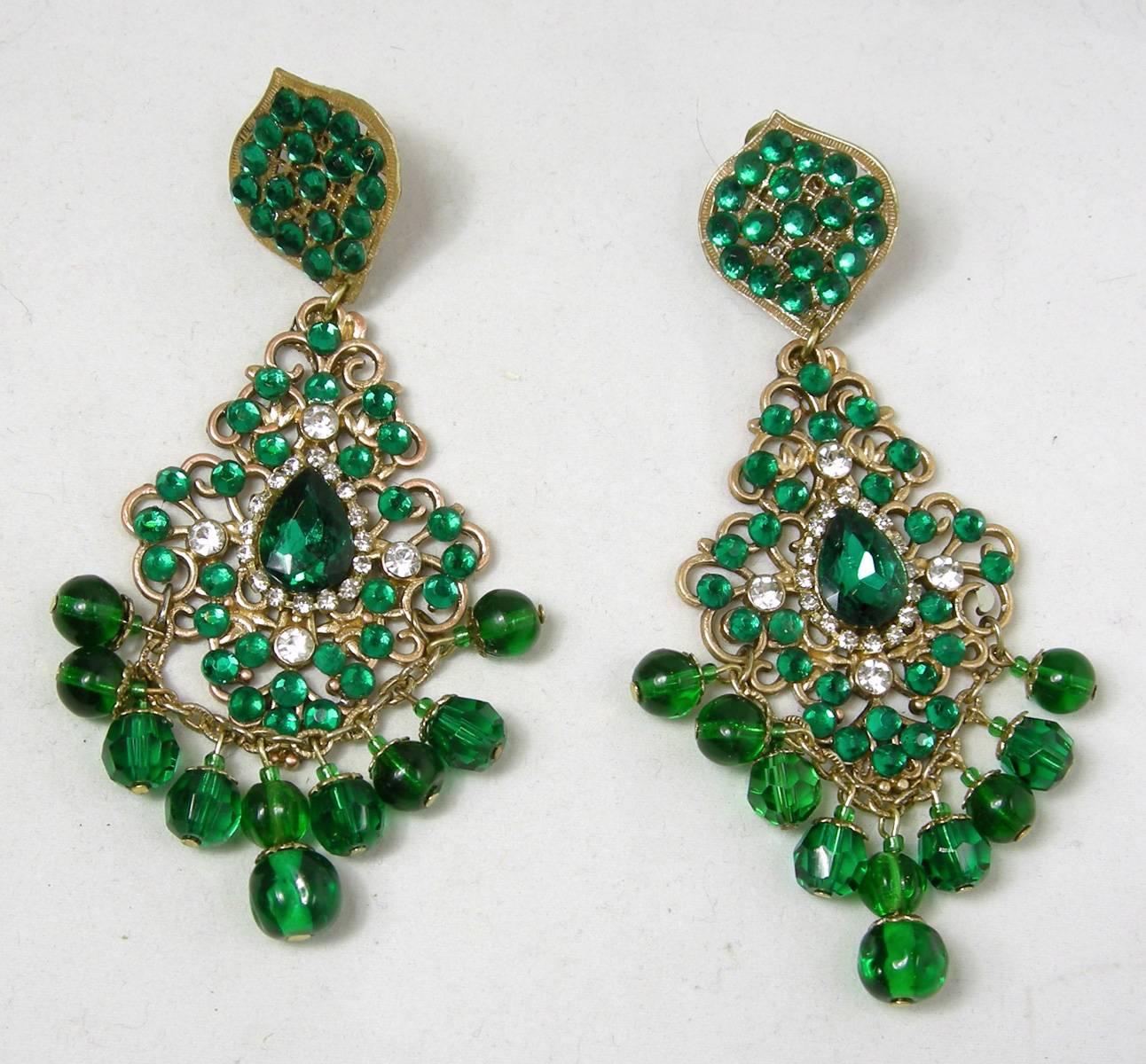 These beautiful vintage DeMario dangling clip earrings has a cluster of green rhinestones at the top in an intricate gold tone setting.  Hanging down is an elaborate design with green rhinestones set in a curly open work setting.  Clear rhinestones