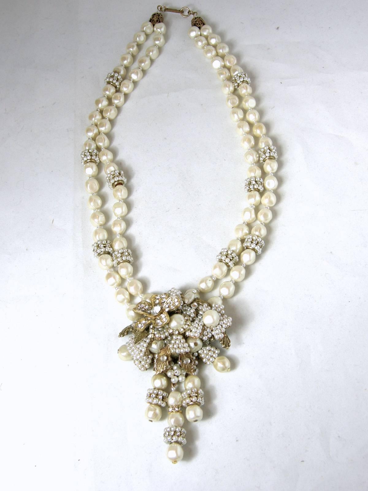 This necklace is an unsigned but it has the old Haskell pull clasp with the patent number.  It has two strands of faux baroque pearls with faux pearl rhondelle dividers leading down to the centerpiece.  The centerpiece has a rhinestone flower and