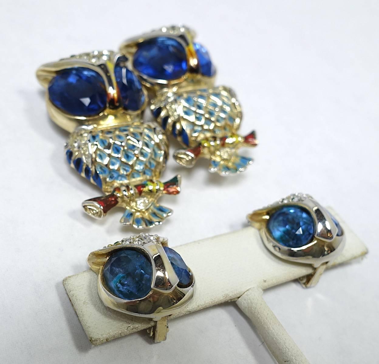This famous vintage owl duette & earrings set by Coro Craft is featured in many of the popular jewelry books.  The owls are perched on a tree branch. They have large blue rhinestone eyes.  The body has clear rhinestones with multi-color enameling