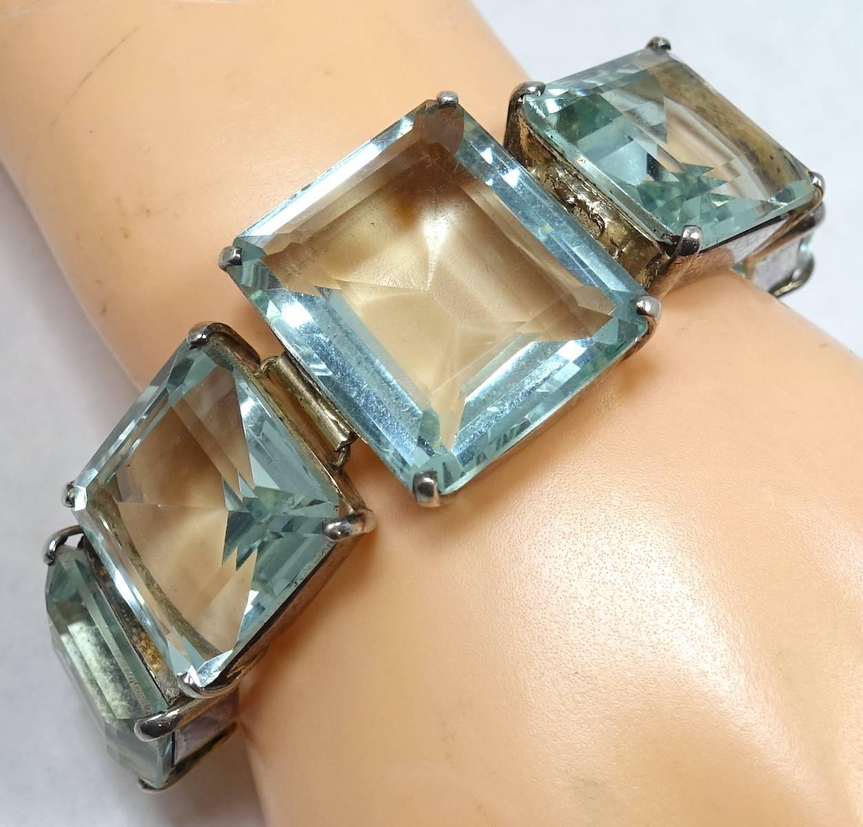 This vintage Deco bracelet features emerald cut aquamarine color crystals in a sterling silver setting.  In excellent condition, this bracelet measures 9-1/4” x 1” and has an adjustable spring closure.