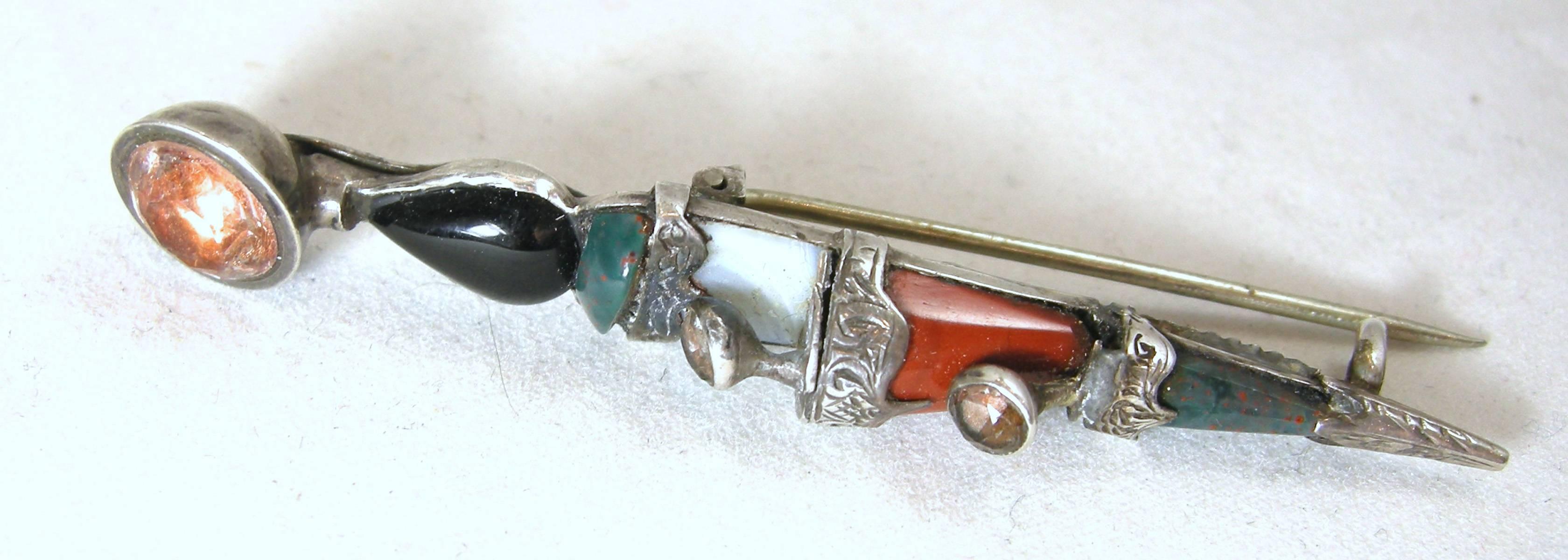 This is a great Scottish scepter/sword sterling silver pin from the 1880s.  It is elongated and most likely used for the kilt.  The top has a citrine gemstone, then onyx followed by different color agates leading to the bottom.  It measures 2-1/2”