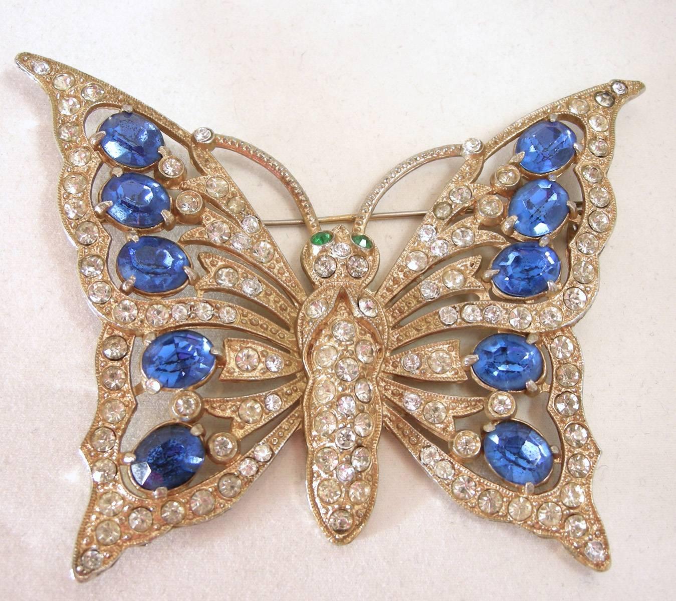 This is one of the most sought after butterfly Staret brooches.  It was made in the 1930s with a gold tone metal finish.  The wings and body have rhinestones throughout its body and green rhinestones for its eyes.  The wings have blue crystals.  It