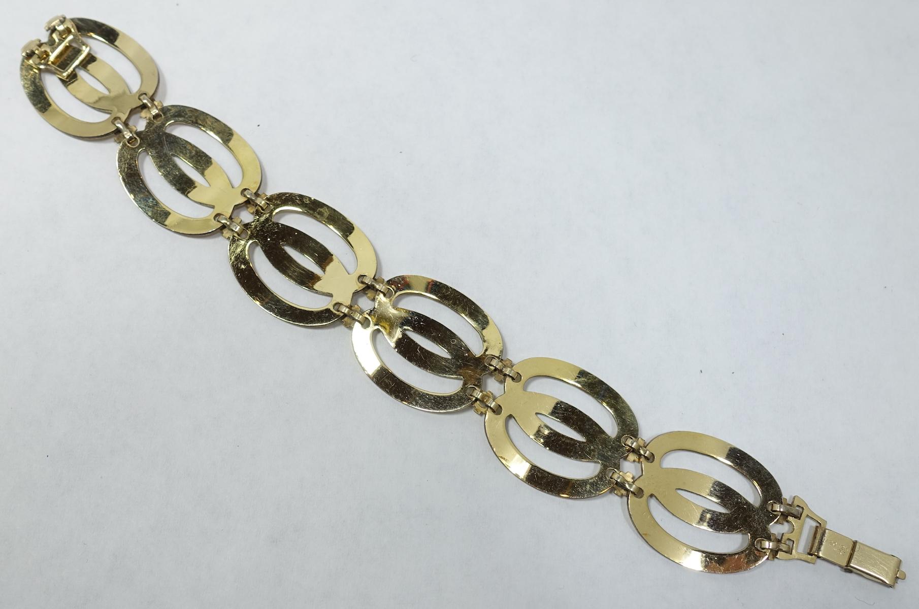This vintage bracelet features gold tone ovals that intertwine over each other. Each oval has an etched design. This bracelet measures 7-1/4” x 1” and is signed “1/20 12k GF” with a fold over clasp. It is in excellent condition. 