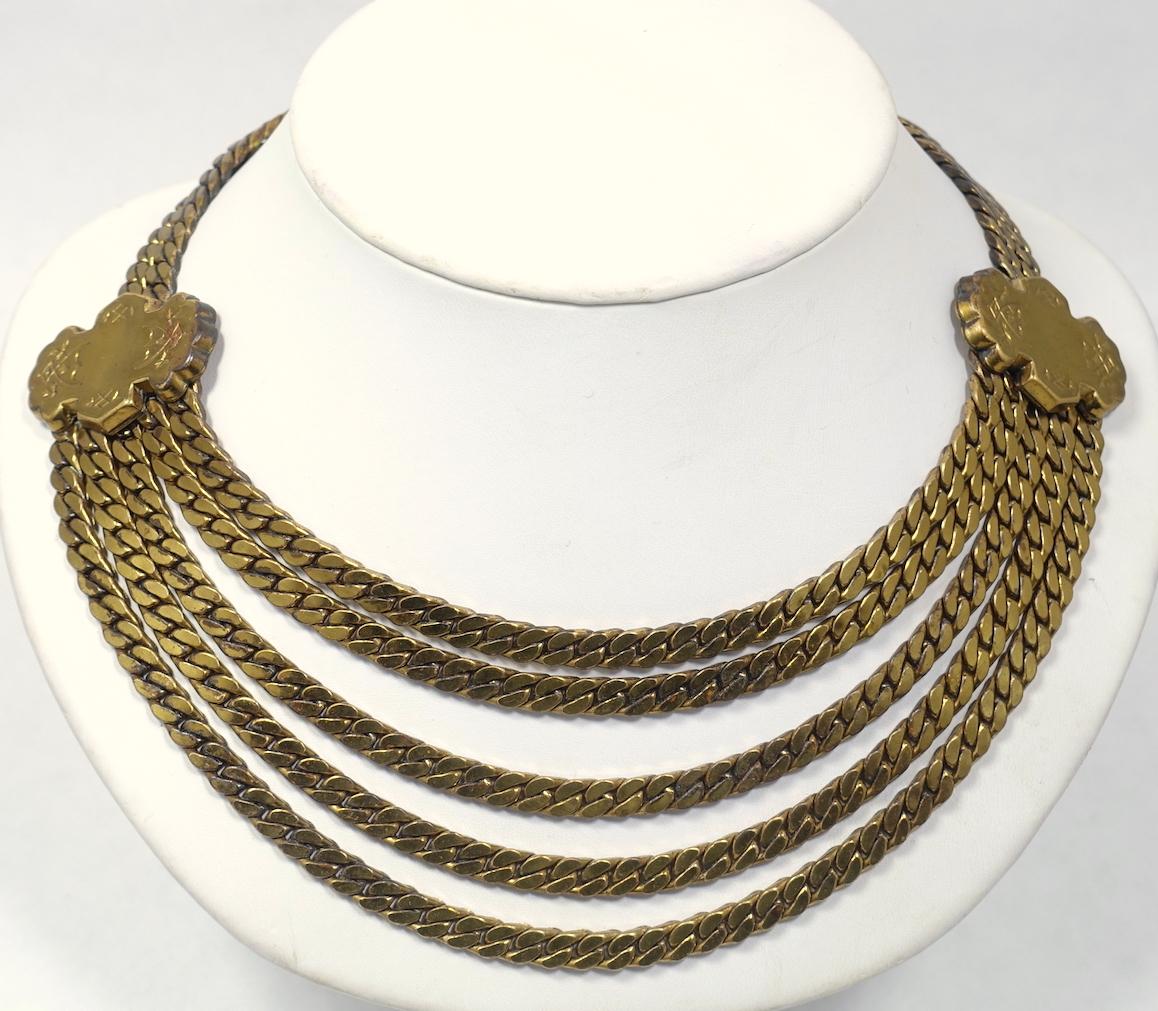 This vintage necklace features 5 strands of link chain in a gold tone setting.  This necklace measures 16” x 1-3/8” with a fold-over clasp and is in excellent condition.