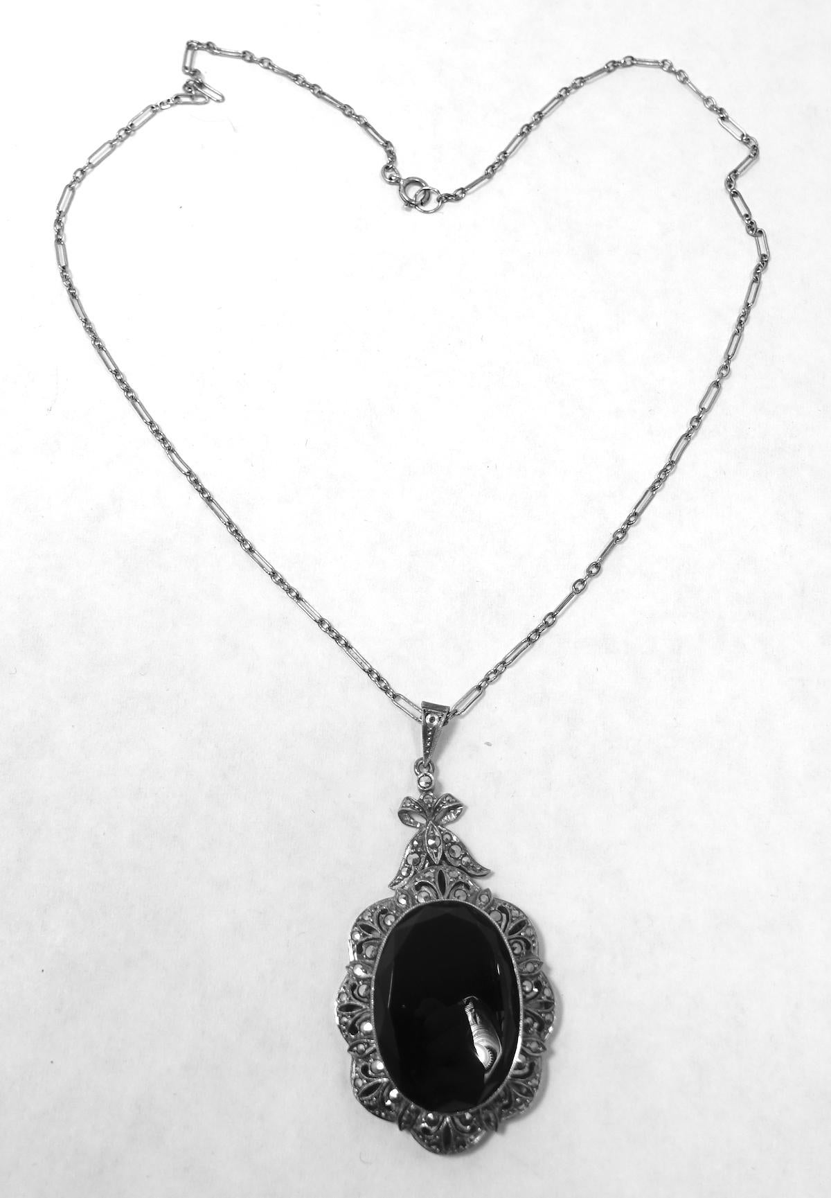 This vintage deco necklace features an oval pendant with onyx and marcasites in a sterling silver setting.  In excellent condition, the oval pendant measures 2-1/8” x 1-1/8”; the sterling link chain is 15-1/2” x 1/16” with a spring back clasp.