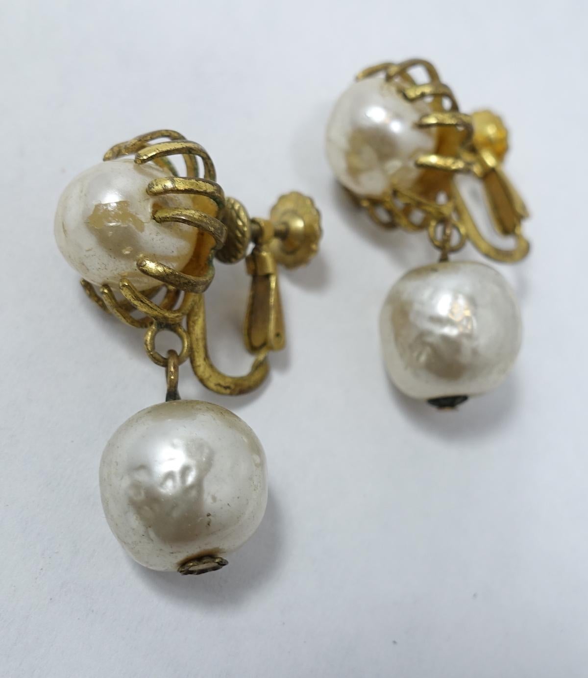 These vintage 1950s Miriam Haskell earrings features faux pearl tops embedded with gold tone prongs. Another faux pearl drop below.  These clip earrings measure 1-1/4” x 1-1/2” and are signed “Miriam Haskell”.  They are in excellent condition.