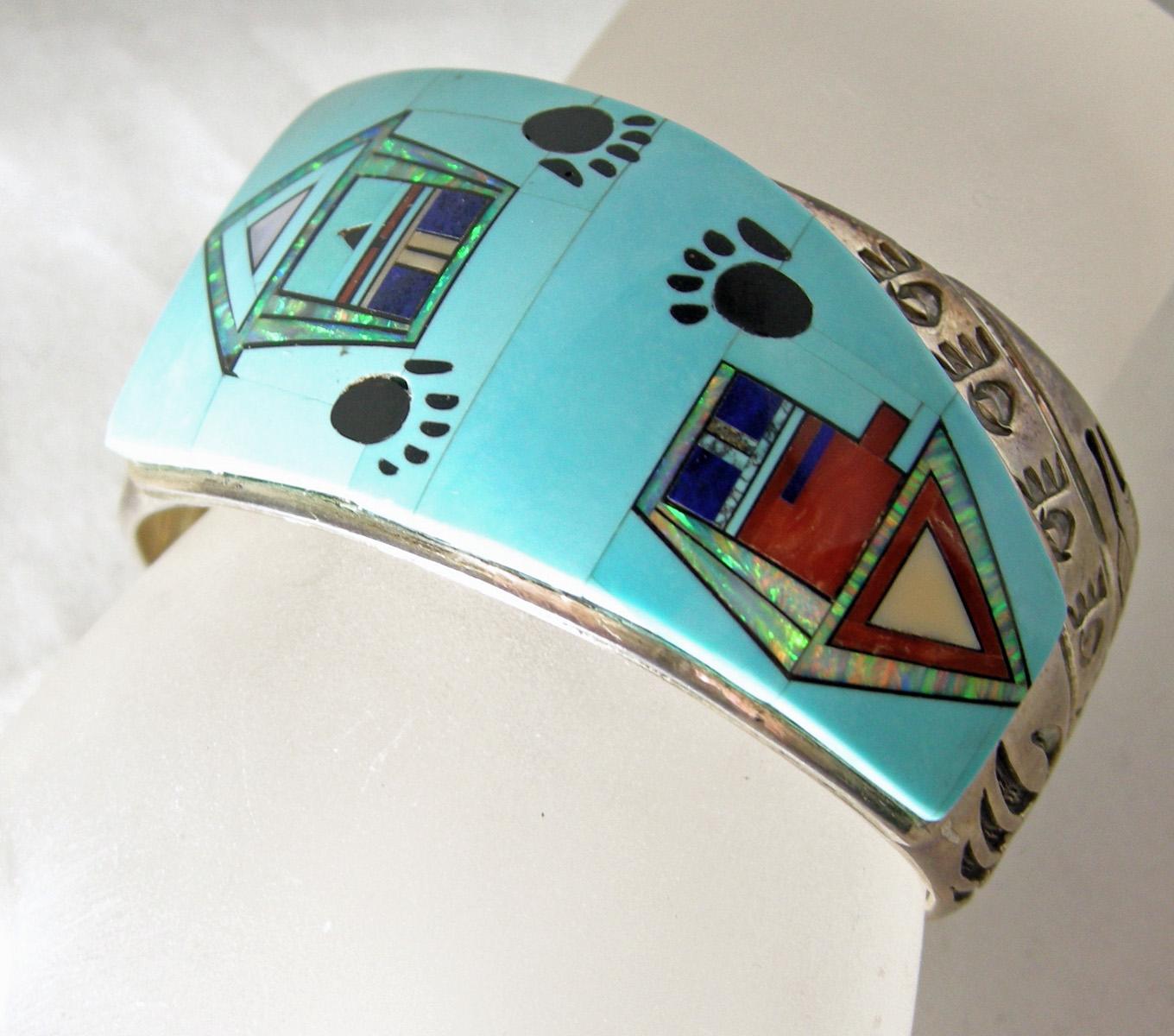 The vintage Zuni sterling silver cuff is very unique.  The front has inlaid turquoise with iridescent designs with paw prints.  The sides have the bear, feathers, and paws of the bear.  It is unique in every way and very rare.  It is 7” x 1-3/8”
