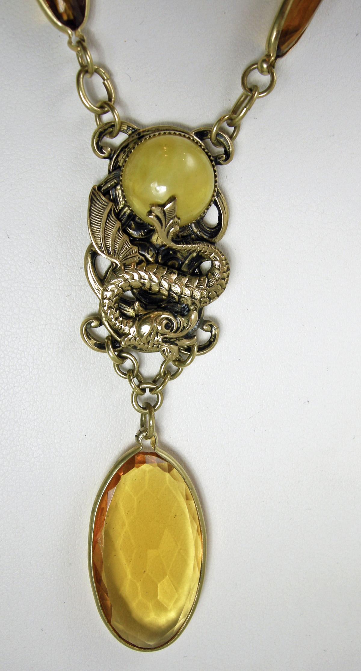 This beautiful old Czech necklace is from the 1930s.  It a gold tone chain attached to elongated faux citrine bezel links streaming down to the center where there is a yellow glass stone being held by a gold tone dragon.  Hanging down from the