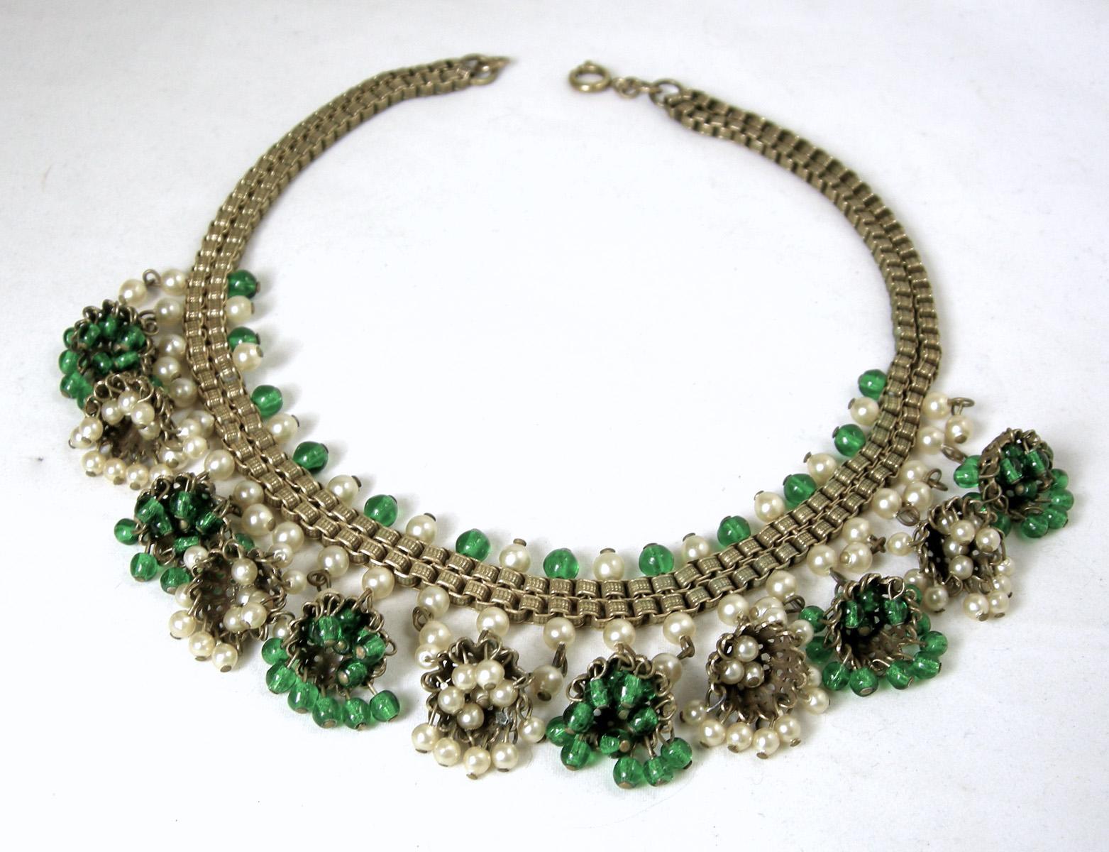 This highly collectible Haskell necklace has French glass with green French glass and tiny pearls in a bell shaped cylinders.  It’s 15-1/2” long with a double box chain that is 1/2” wide.  It has a swing back clasp and antique gold tone finish. 