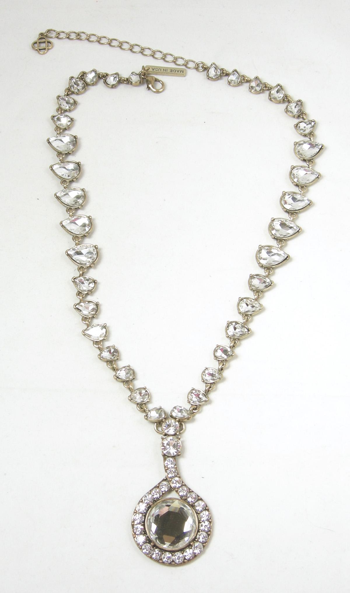 This sophisticated Oscar de la Renta necklace has clear crystals in a gold tone metal leading down to large crystal drop.  The necklace is adjustable up to 22”.  The centerpiece is 2-1/2” x 1-1/2”.  It is signed “Oscar de la Renta” and “Made in USA”