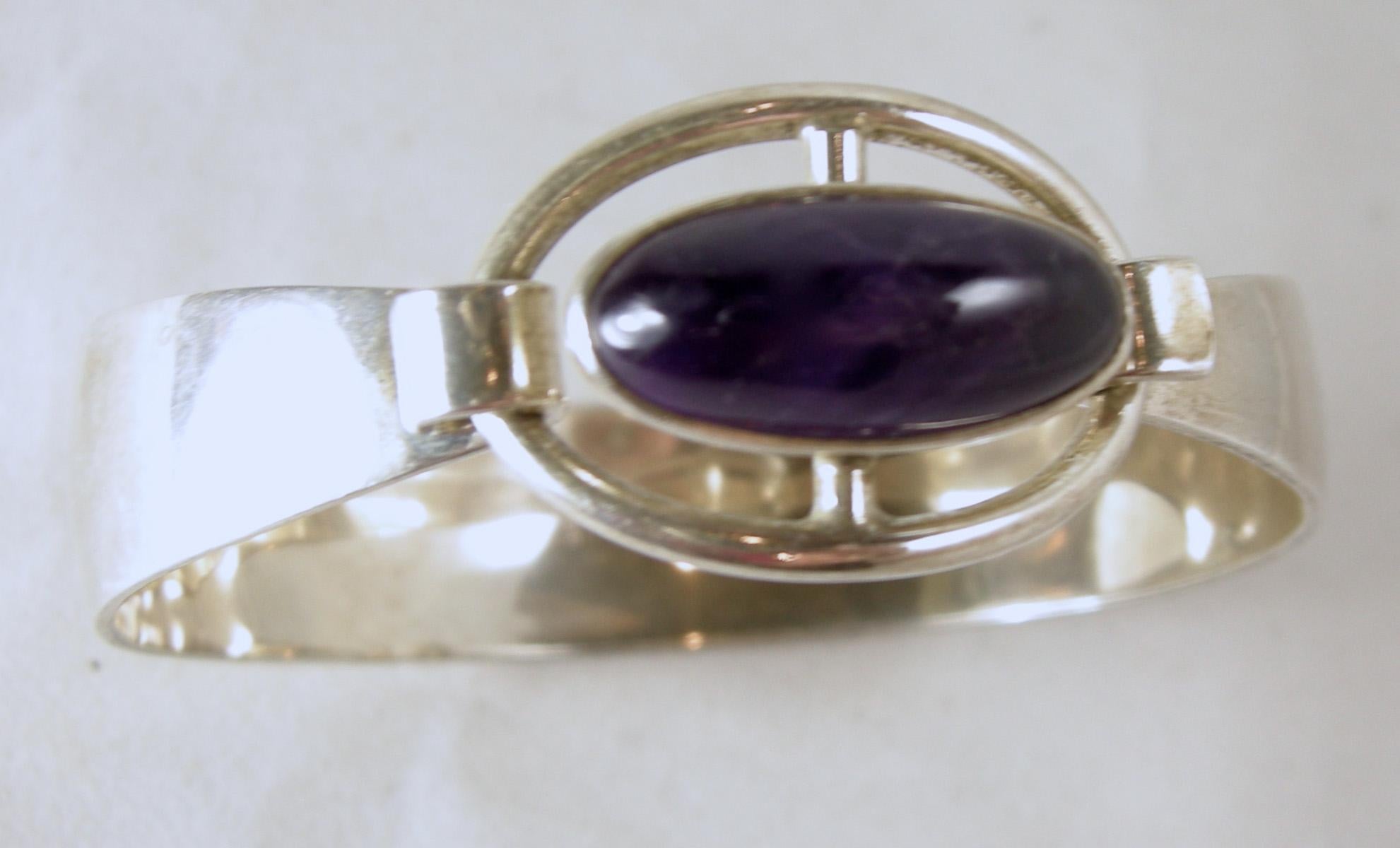 This is a sterling silver bracelet with an oval amethyst center.  I never tested the stone, so I don’t know if it’s real.  It has a front latch to open.  It measures 6-1/2” x 5/8” wide at its widest point.  It is marked “sterling Silver 925 Denmark”
