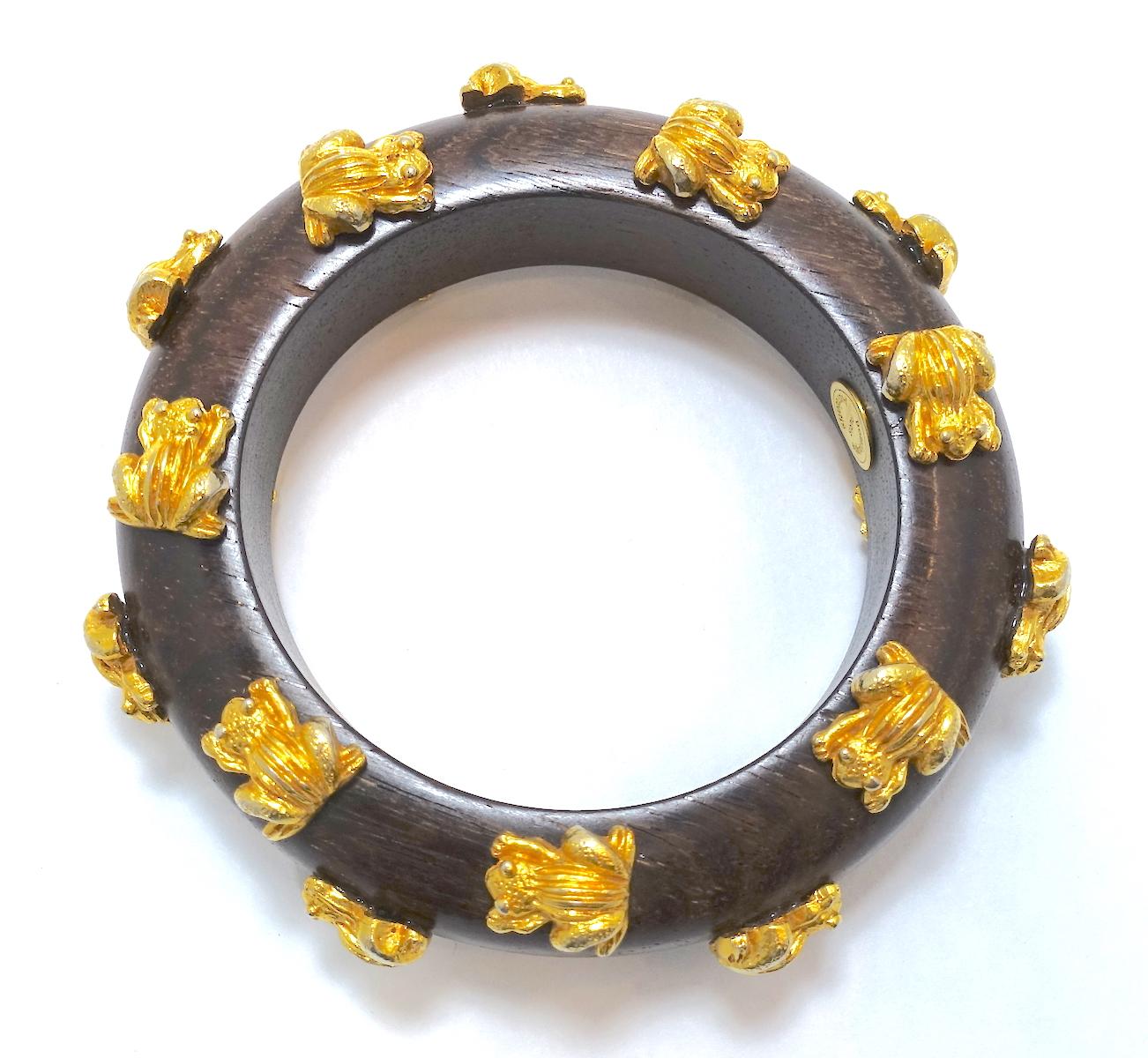 This vintage, very collectible signed Dominique Aurientis bangle bracelet features 3-dimensional gold tone frogs all along the wood bangle.  This piece measures 7-1/2” around the inside x 3/4” wide and is signed “Dominique Aurientis”.  It is in