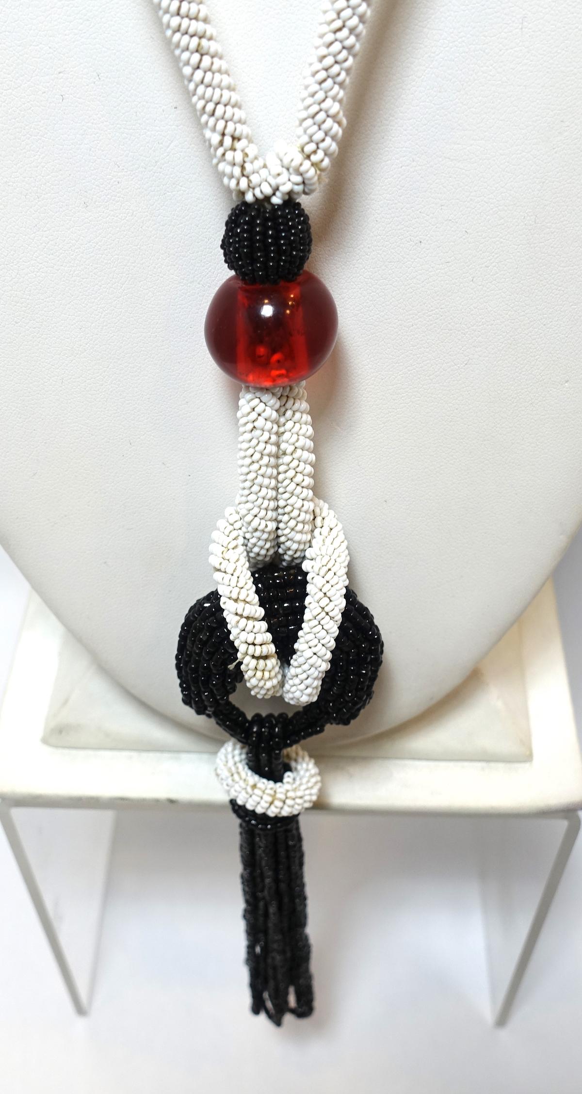 This vintage Art Deco 1920s flapper necklace features black and white beads with large cranberry red bead accents in a silver tone setting.  This necklace measures 22” long with a screw barrel closure.  The tassel is 6-1/2” top to bottom.  This