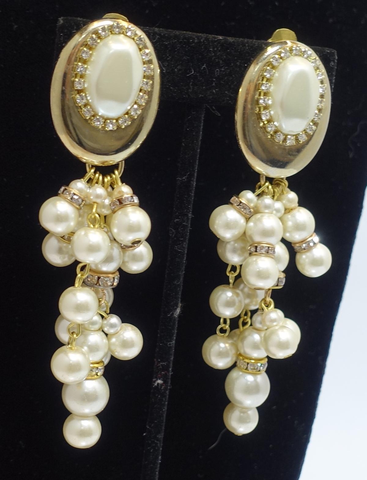These vintage signed DeMario earrings feature faux pearls with clear rhinestone accents in a gold tone setting.  These clip earrings measure 3-1/2” long x 1” wide and signed “DeMario”. They are in excellent condition.