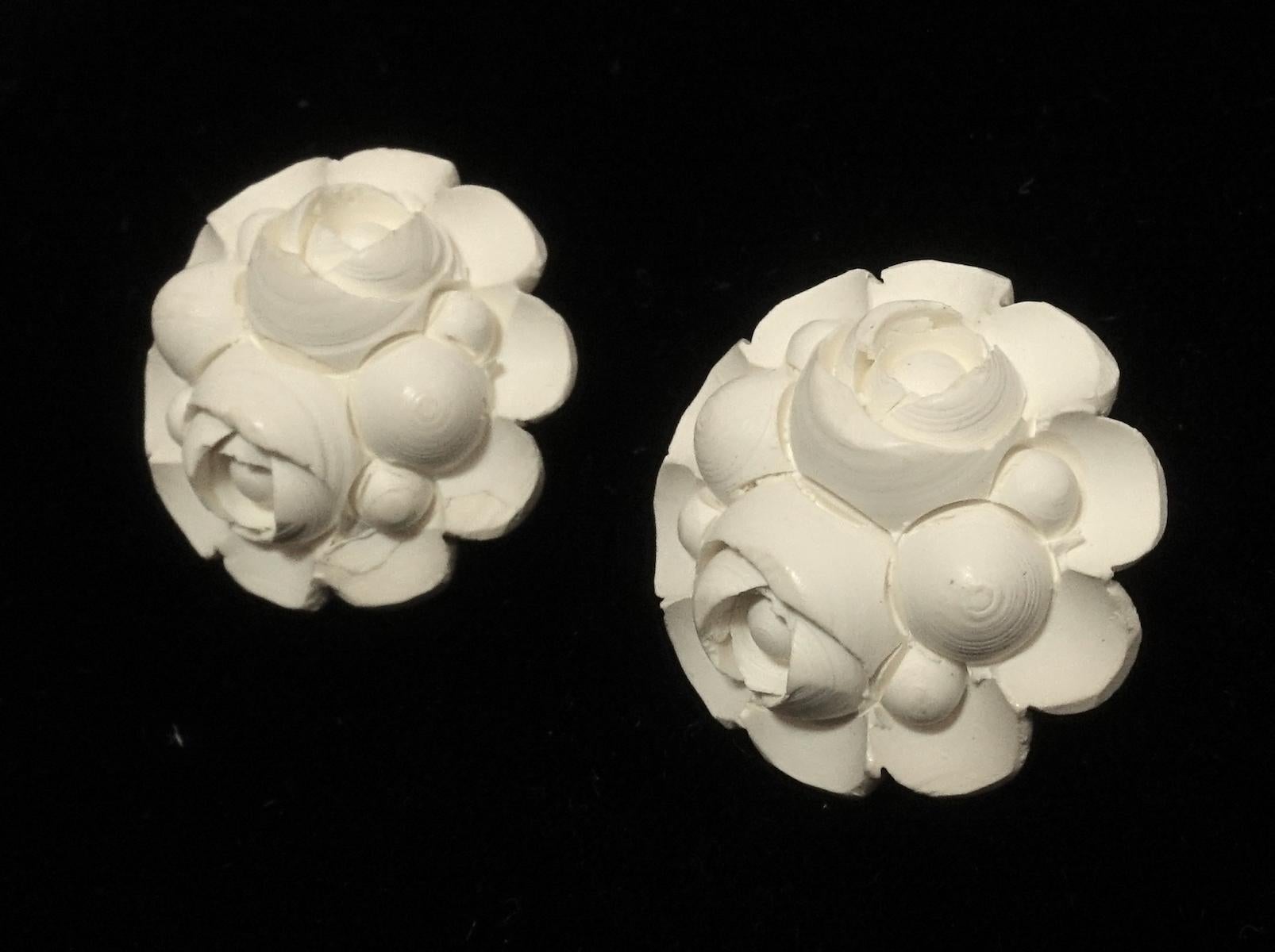 These vintage 1950s earrings feature a floral design in white resin in a gold tone setting.  These clip earrings measure 3/4” in diameter and are in excellent condition.