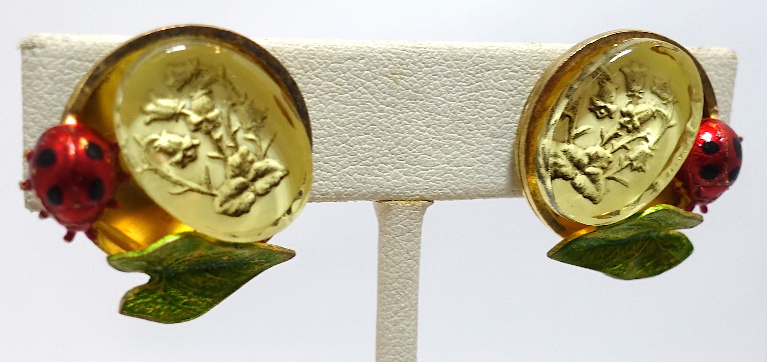 These vintage signed Claudine Vilry Paris earrings feature a floral intaglio accented by an enameled bumble bee and leaf in a gold tone setting.  These clip earrings measure 1” x 1” and are signed “Claudine Vilry Paris”. They are in excellent