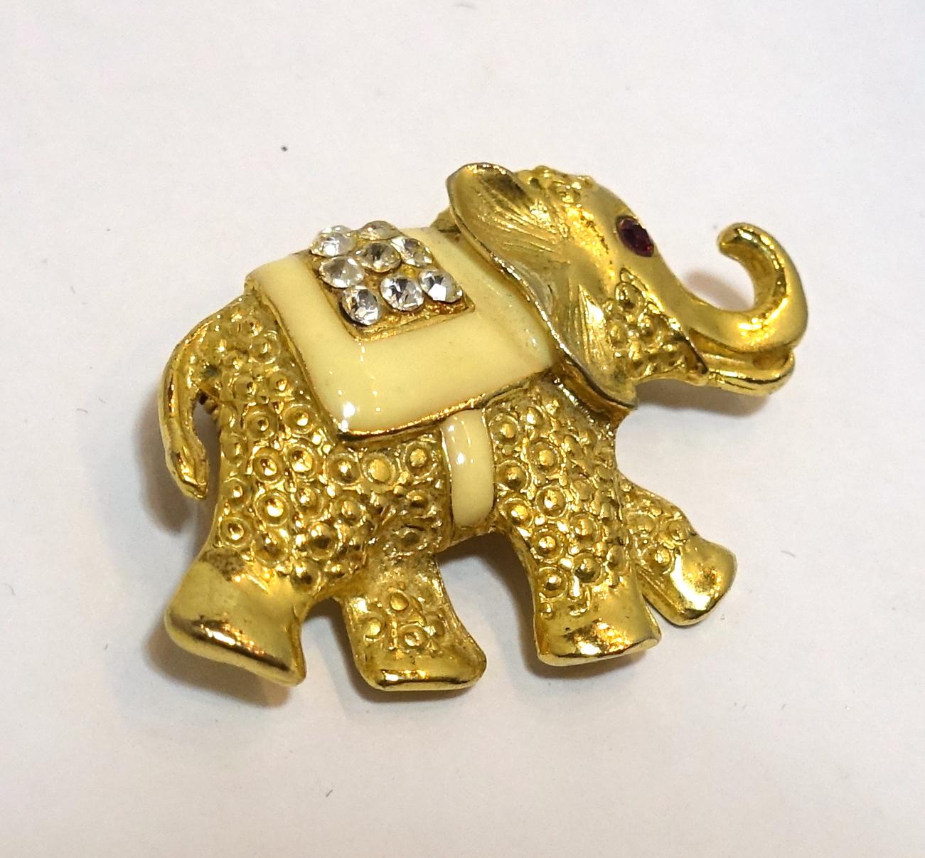 This vintage 1960s brooch features an elephant design with ivory color enameling and clear crystal accents in a gold tone setting.  This elephant brooch measure 2” x 1” and is in excellent condition.