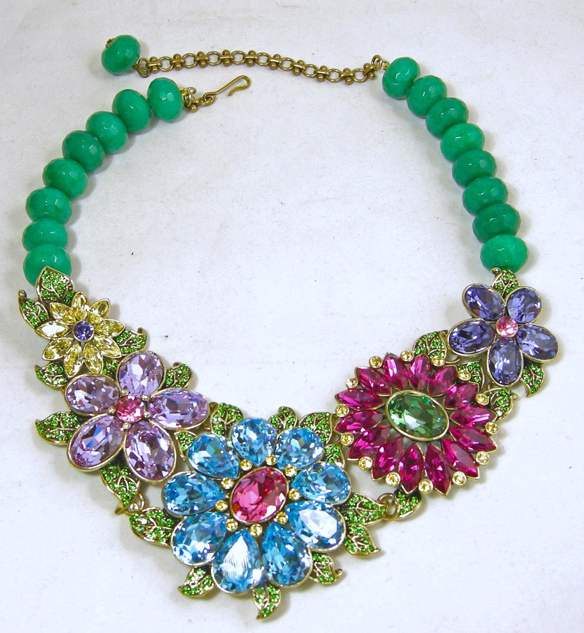 This Heidi Daus necklace has green glass beads with a hook clasp leading downward to a magnificent array of beautiful 3-dimensional flowers that graduate in size.  The flowers are decorated with vibrant crystals of citrine, light amethyst,