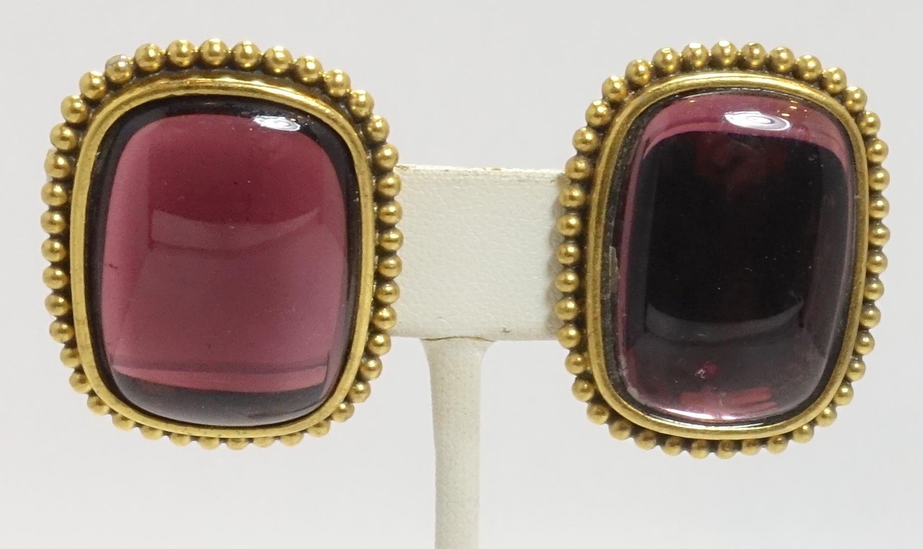 These vintage signed Yves St. Laurent earrings feature amethyst color poured glass in a gold-tone metal setting.  These clip earrings measure 1-3/8” x 1”, are signed “YSL”, and are in excellent condition.