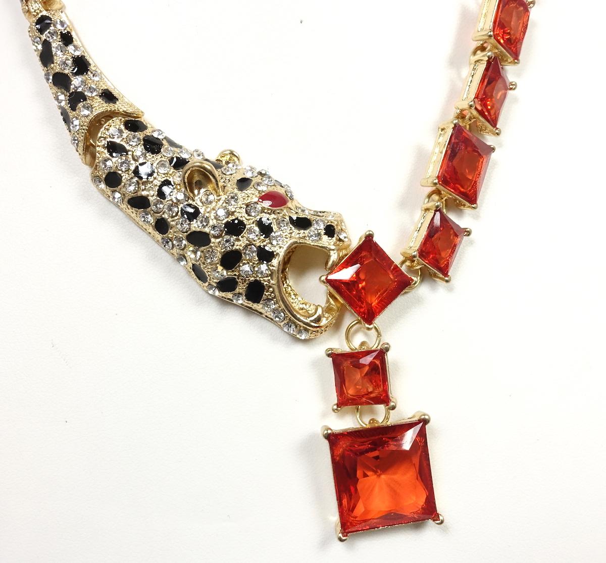 This necklace is made with a gold tone metal with the leopard’s mouth capturing red crystal squares.  The links to this necklace have the leopard’s body encrusted with rhinestones with black enamel dots right up to the fold-over clasp.  This