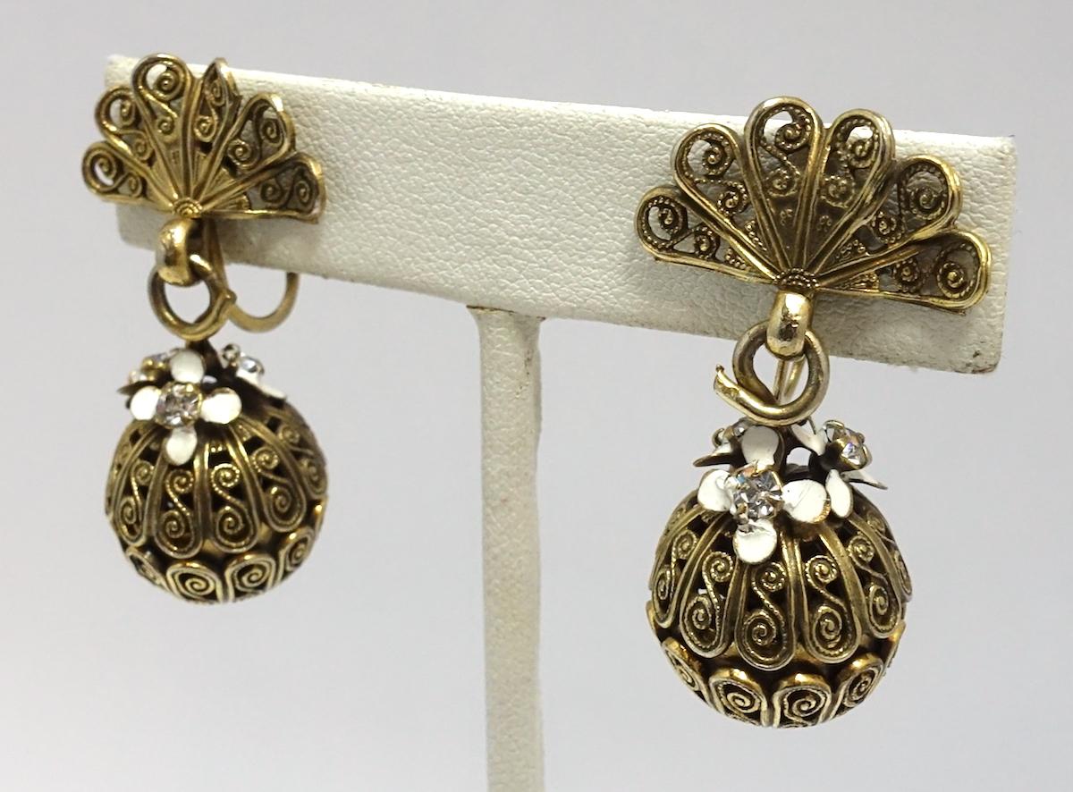 These vintage earrings feature white enamel flowers with clear crystal accents in a gold-tone setting.  These clip earrings measure 1-1/2” x 5/8” and are in excellent condition.