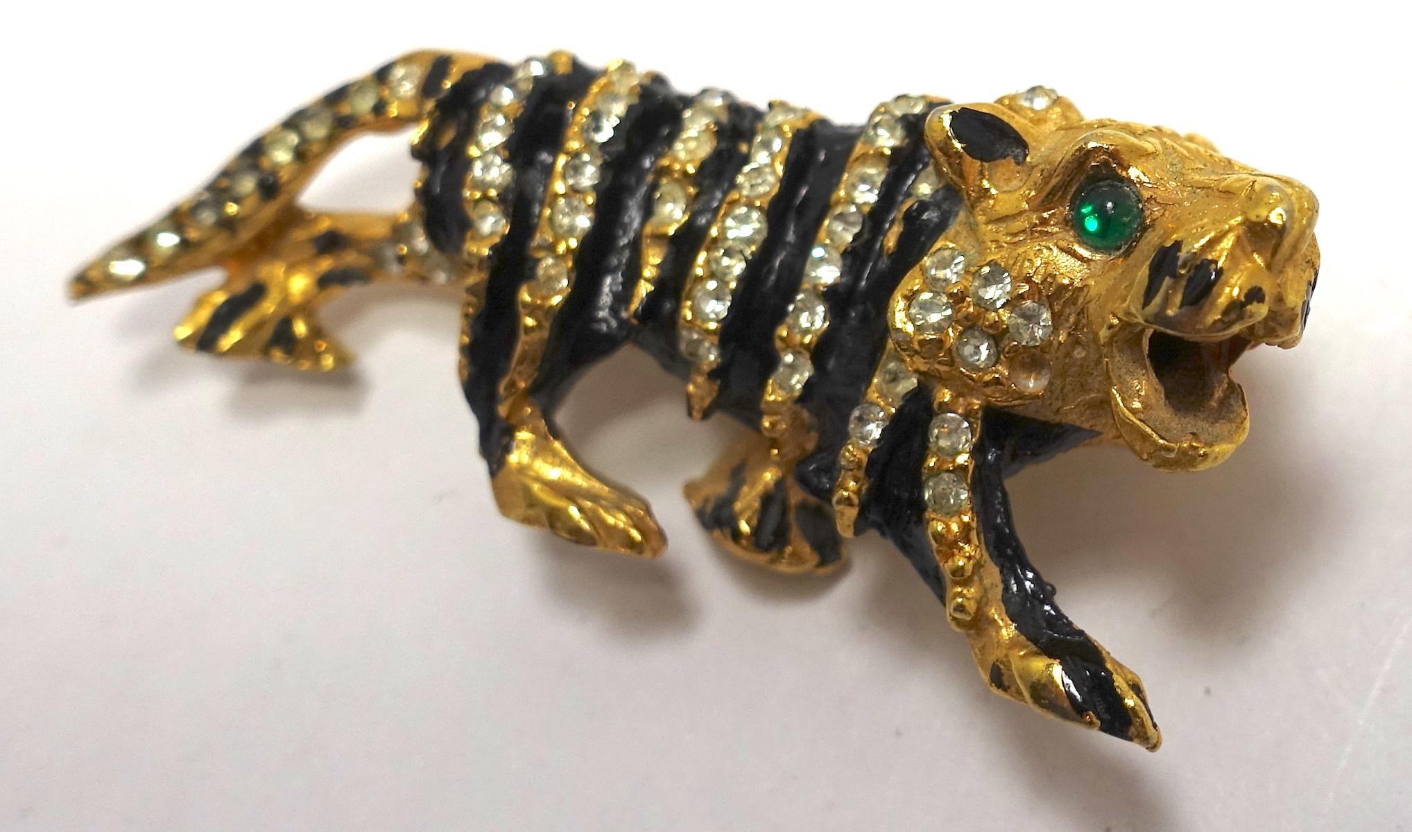This vintage tiger brooch bears the old “K.J.L.” signature from the 1960s. This piece has black enameling with clear and green crystal accents in a gold-tone setting.  This brooch measures 2-1/4” x 7/8”, is signed “K.J.L.”, and is in excellent