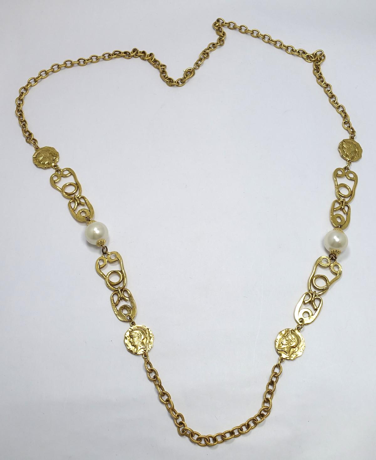 This necklace features discs with a figure of a Roman soldier accented by faux pearls in a gold-tone setting.  This piece measures 44” x ¾” with a spring closure and is in excellent condition.