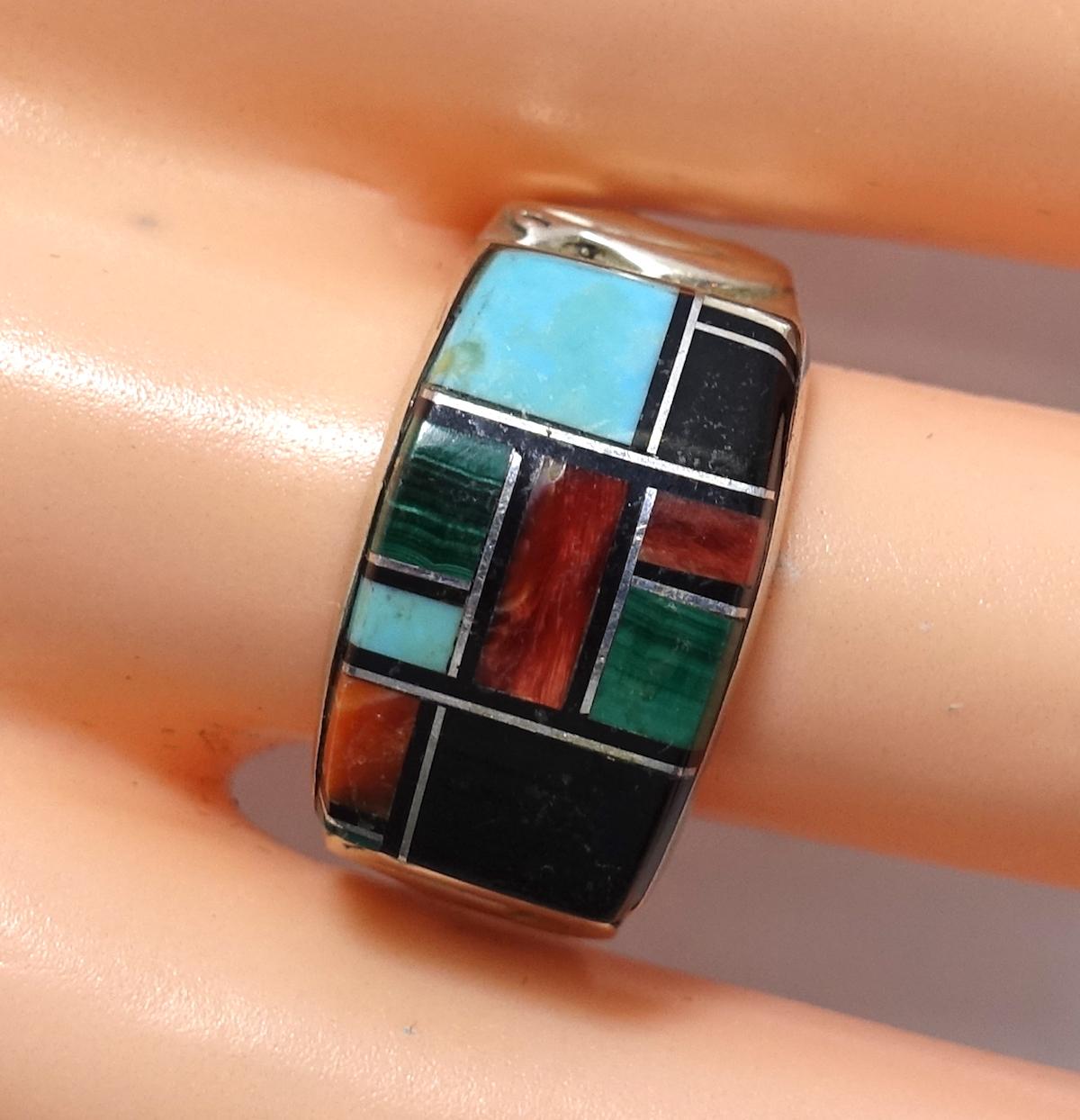 This vintage ring features turquoise, coral, lapis and malachite stones in a sterling silver setting.  A size 8.5+, this ring measures ½” at the top, is signed “OT” and is in excellent condition.