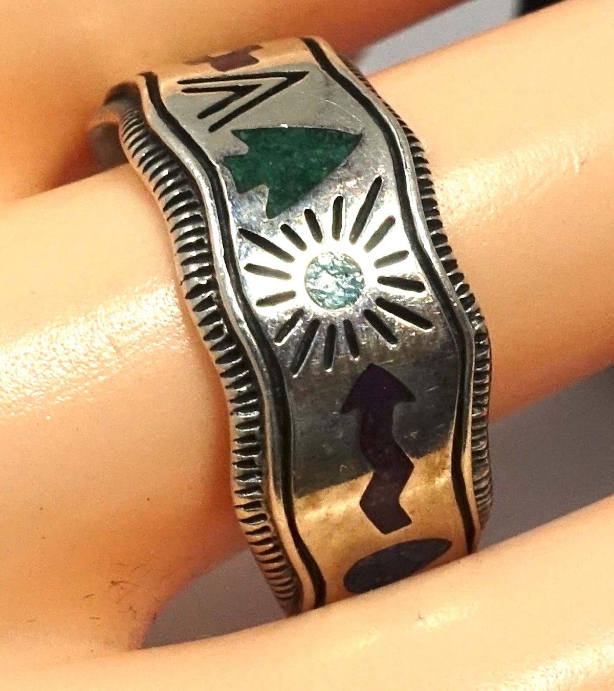 This vintage signed CQS ring features symbols with turquoise & coral accents in a sterling silver setting.   A size 10, this piece measures 3/8” wide, is signed “CQS Sterling” and is in excellent condition.