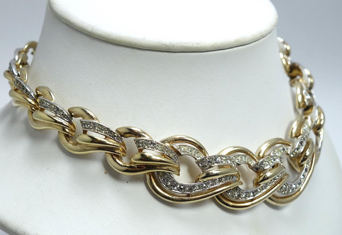 This vintage signed Boucher necklace has interlocking clear crystal links in a gold tone setting.  This necklace measures 16” x 1” with a fold-over clasp. It is signed “Boucher” and is in excellent condition.