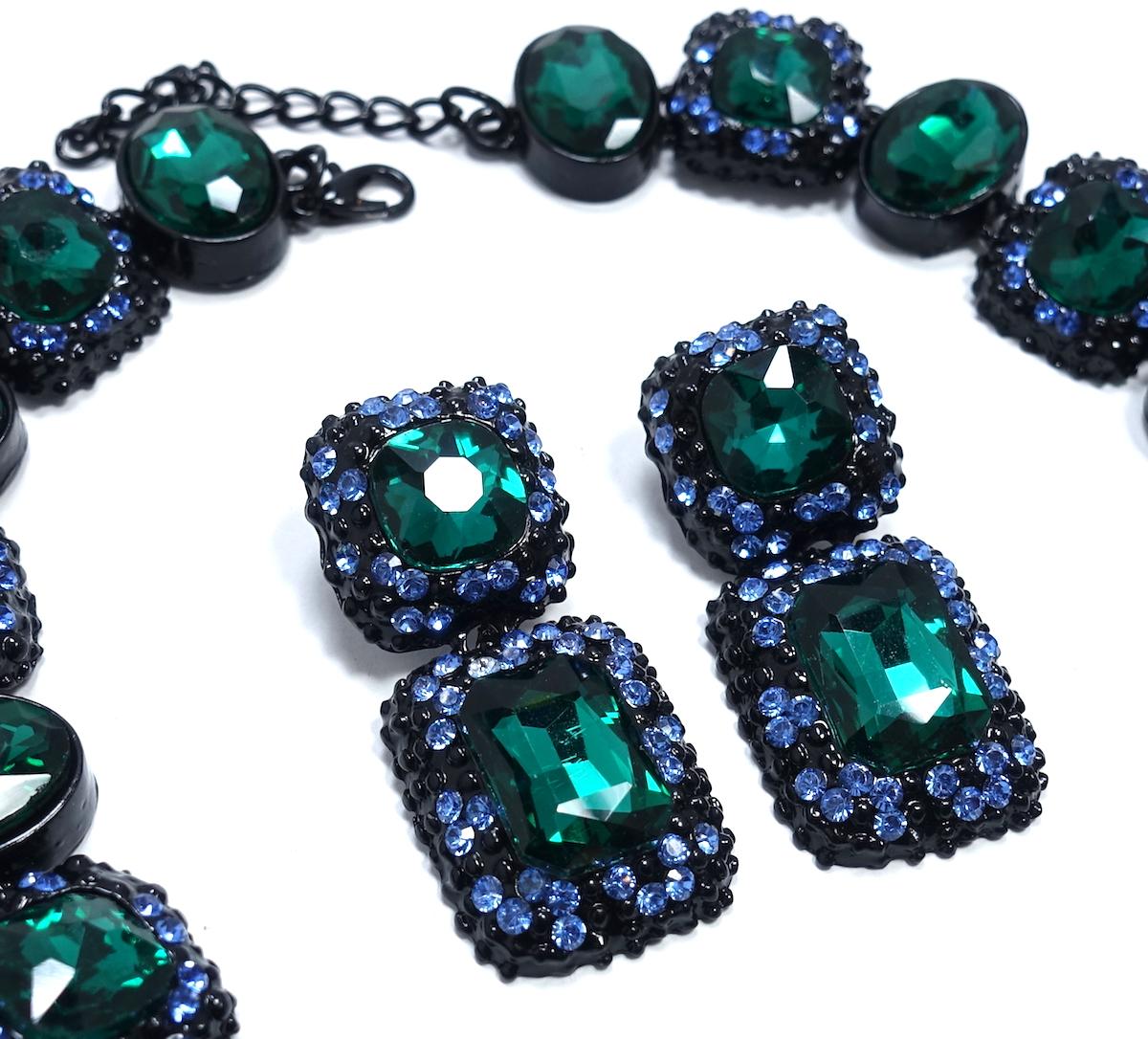 This stunning necklace & earrings feature rich emerald green square and oval shaped crystals with blue crystal accents in a black Japanned setting. The necklace measures 18-1/2” x 3/4” and the front drop is 2-1/2” x 1-1/2” wide. The matching pierced