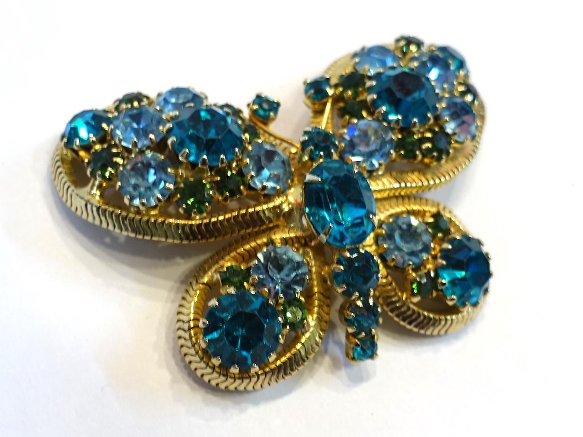 This vintage signed brooch features a dragonfly with blue and turquoise color crystals in a gold tone setting.  In excellent condition, this brooch measures 2” x 1-1/2” and is signed “Weiss”.